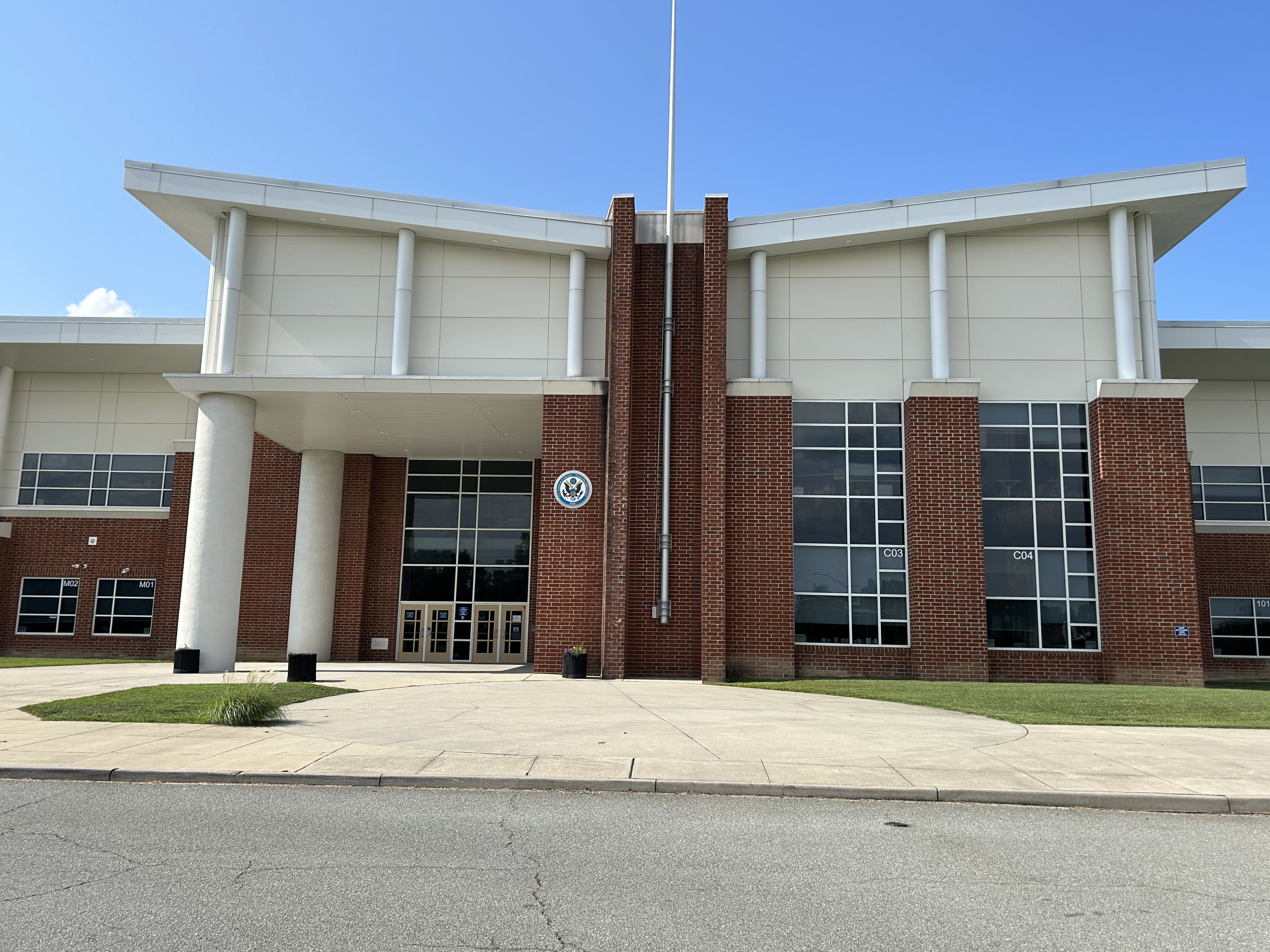 Brick school building exterior with flagpole and large glass windows.