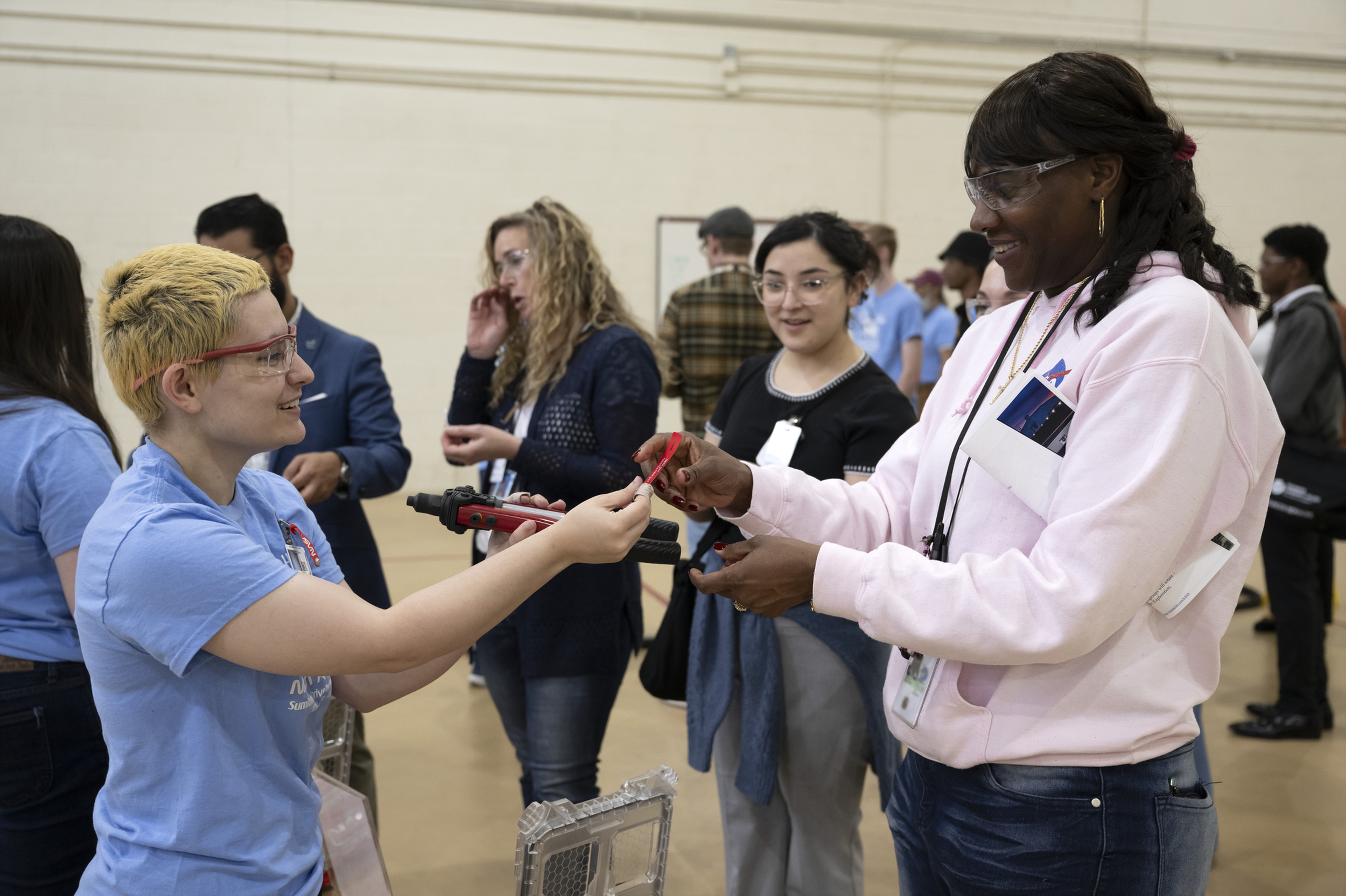 Two students exchanging materials during a hands-on STEM learning activity indoors.