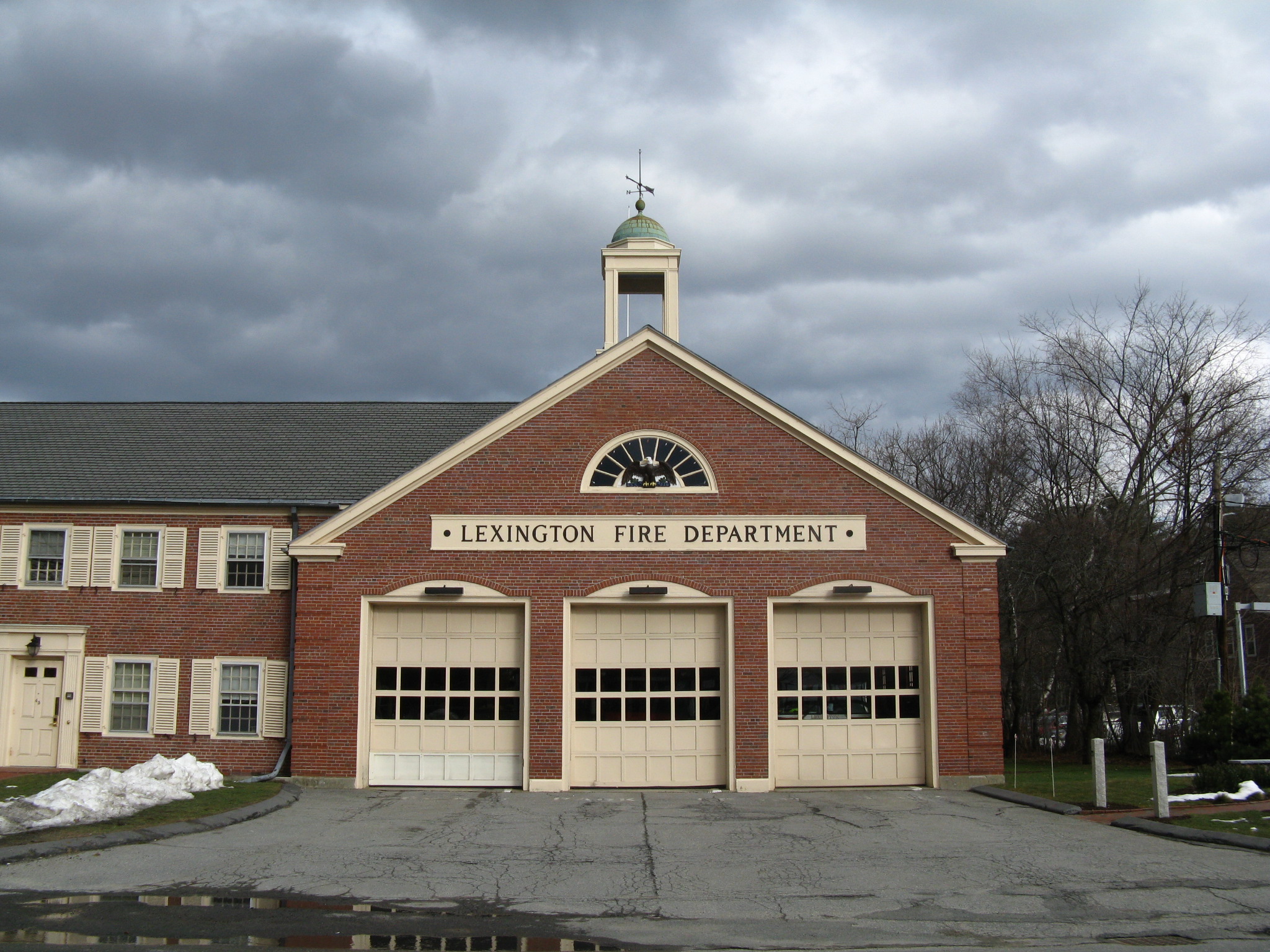 Red brick fire station with three apparatus bays and a cupola, labeled Lexington Fire Department.