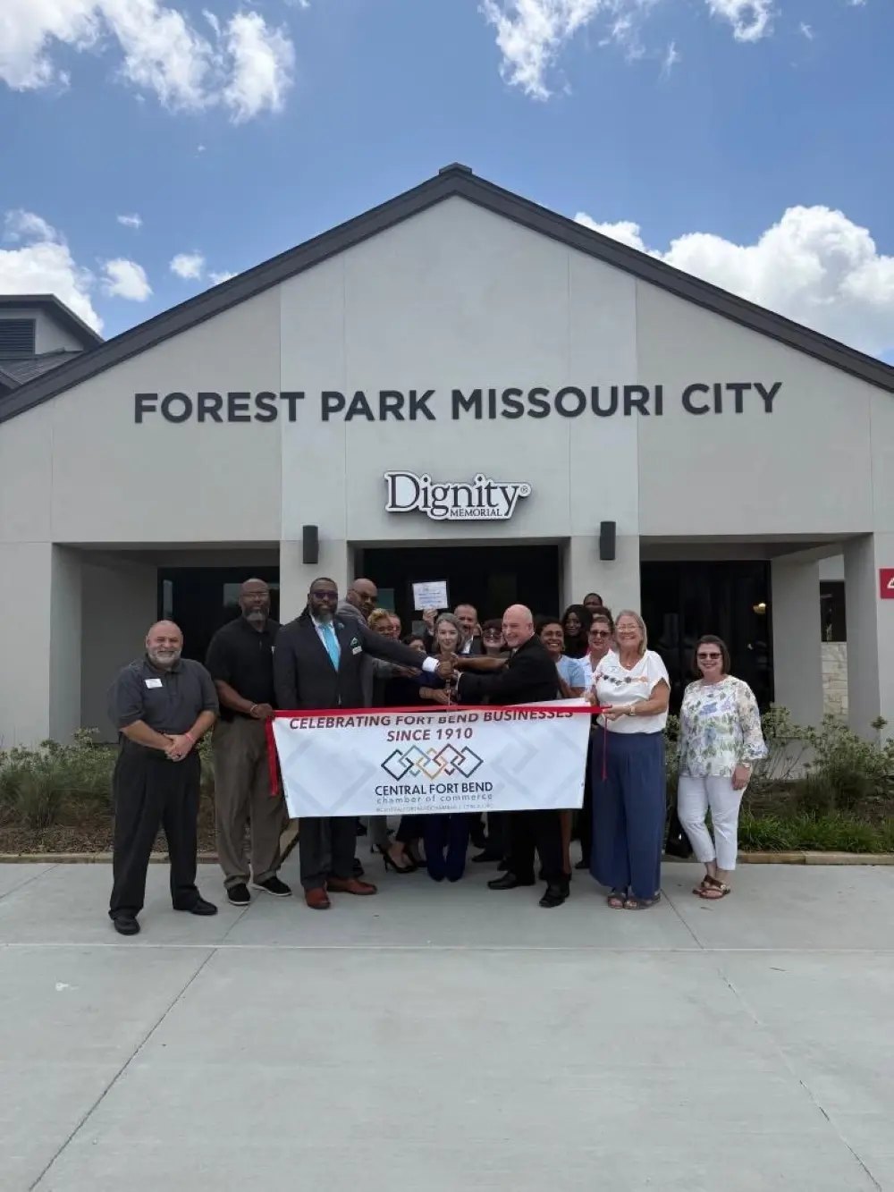 Group of people standing in front of a building holding a Central Fort Bend Chamber of Commerce banner.