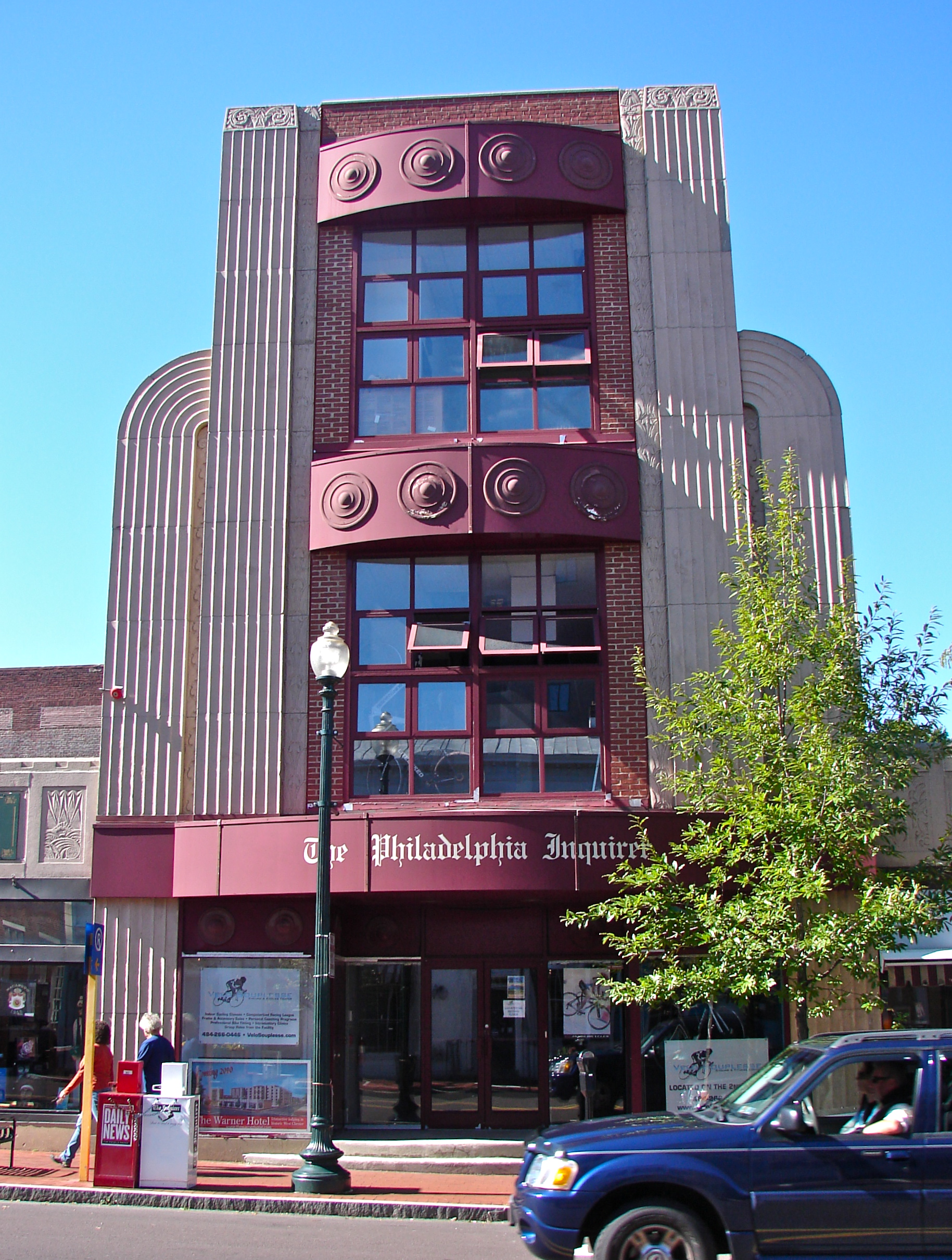 Multi-story Art Deco building with maroon and tan facade on a downtown street.