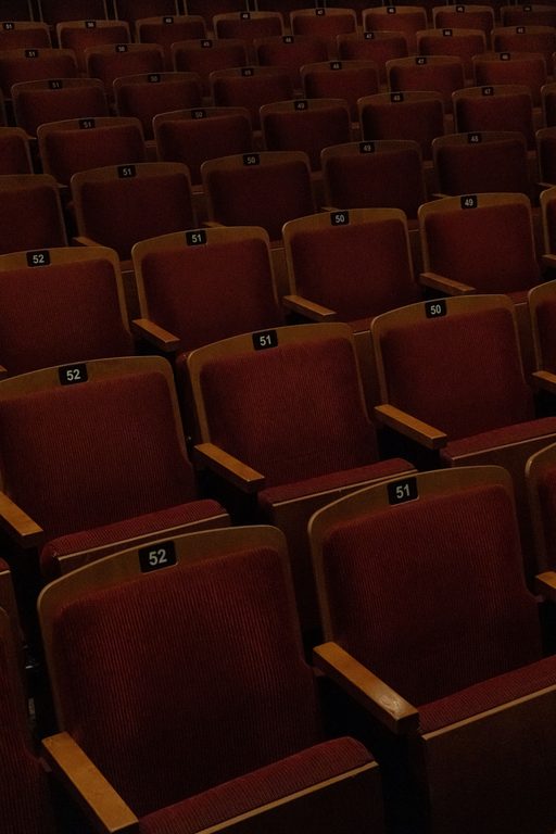 Rows of red theater seats in an empty auditorium, ready for an audience.