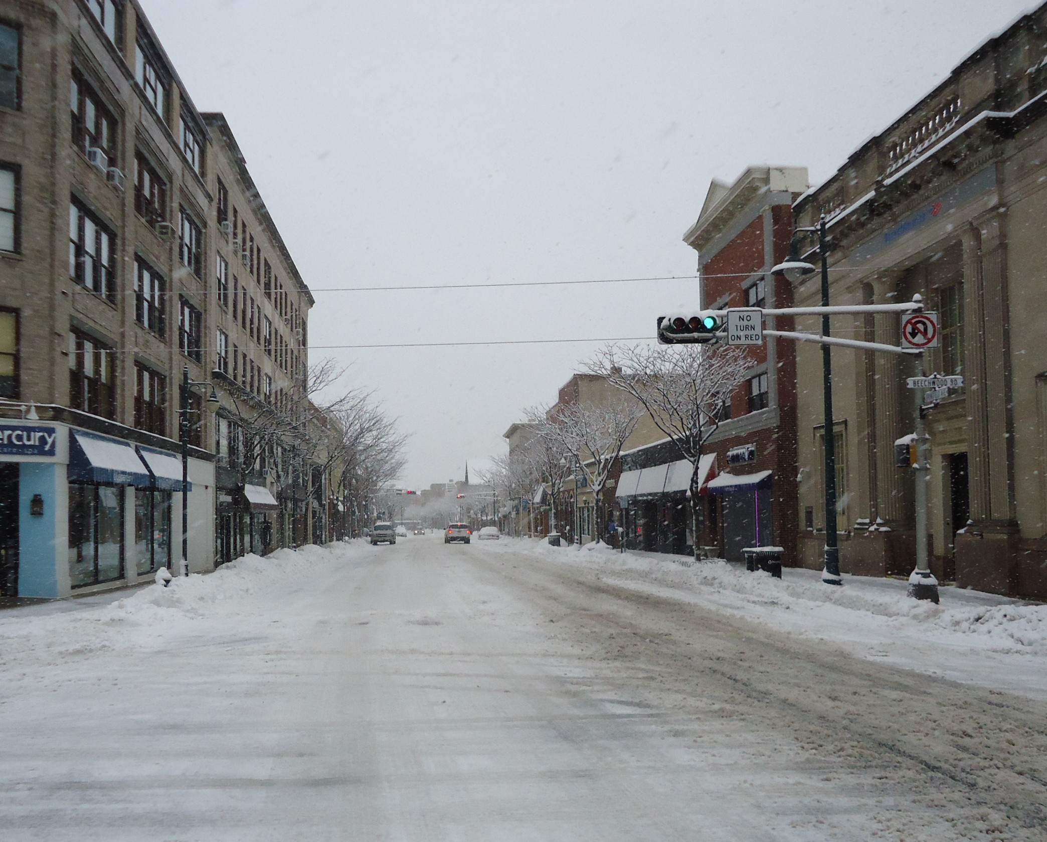 Snow-covered Springfield Avenue in downtown Summit lined with brick commercial buildings.