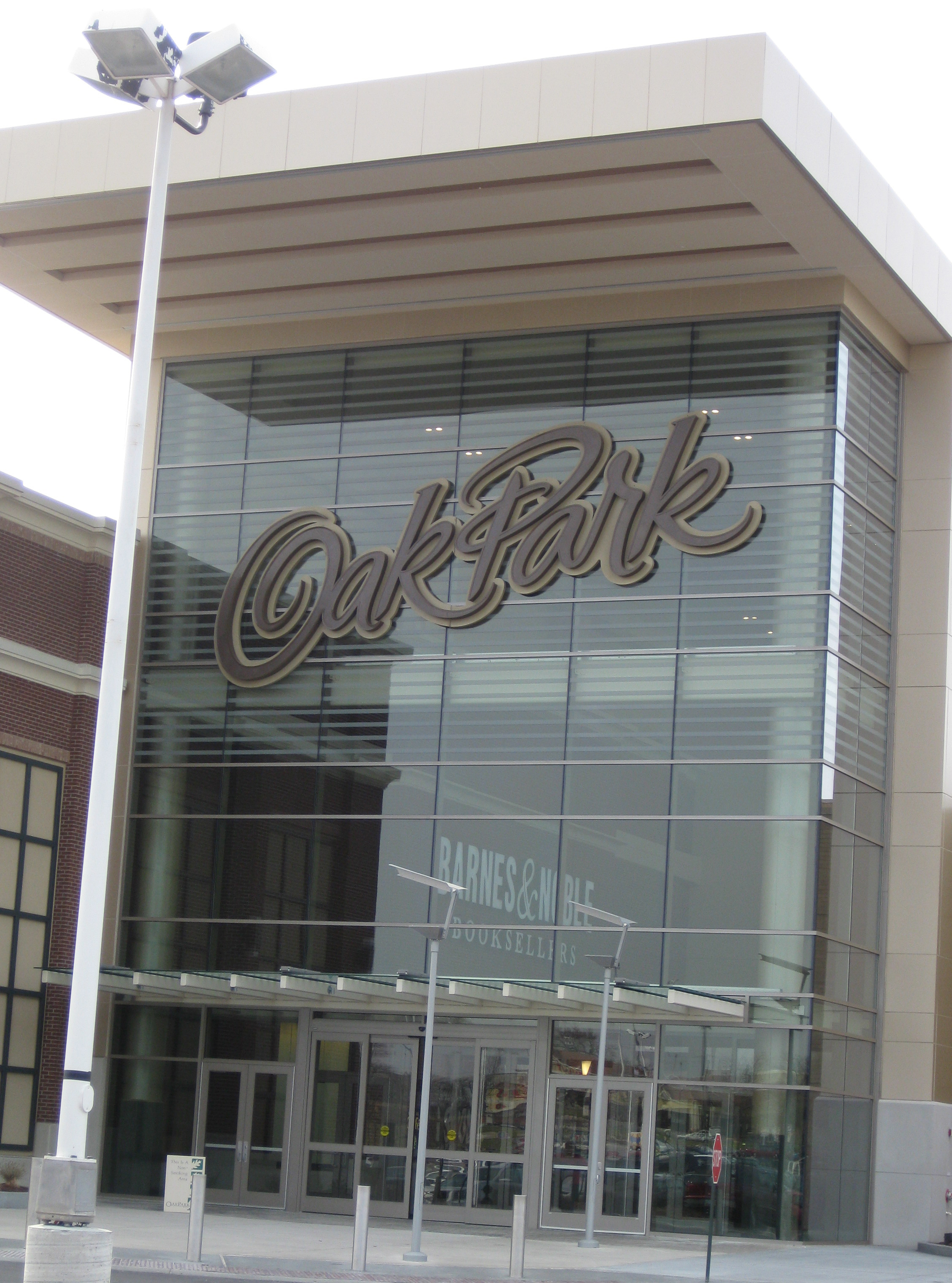 Glass entrance facade of a shopping mall with a large cursive sign.