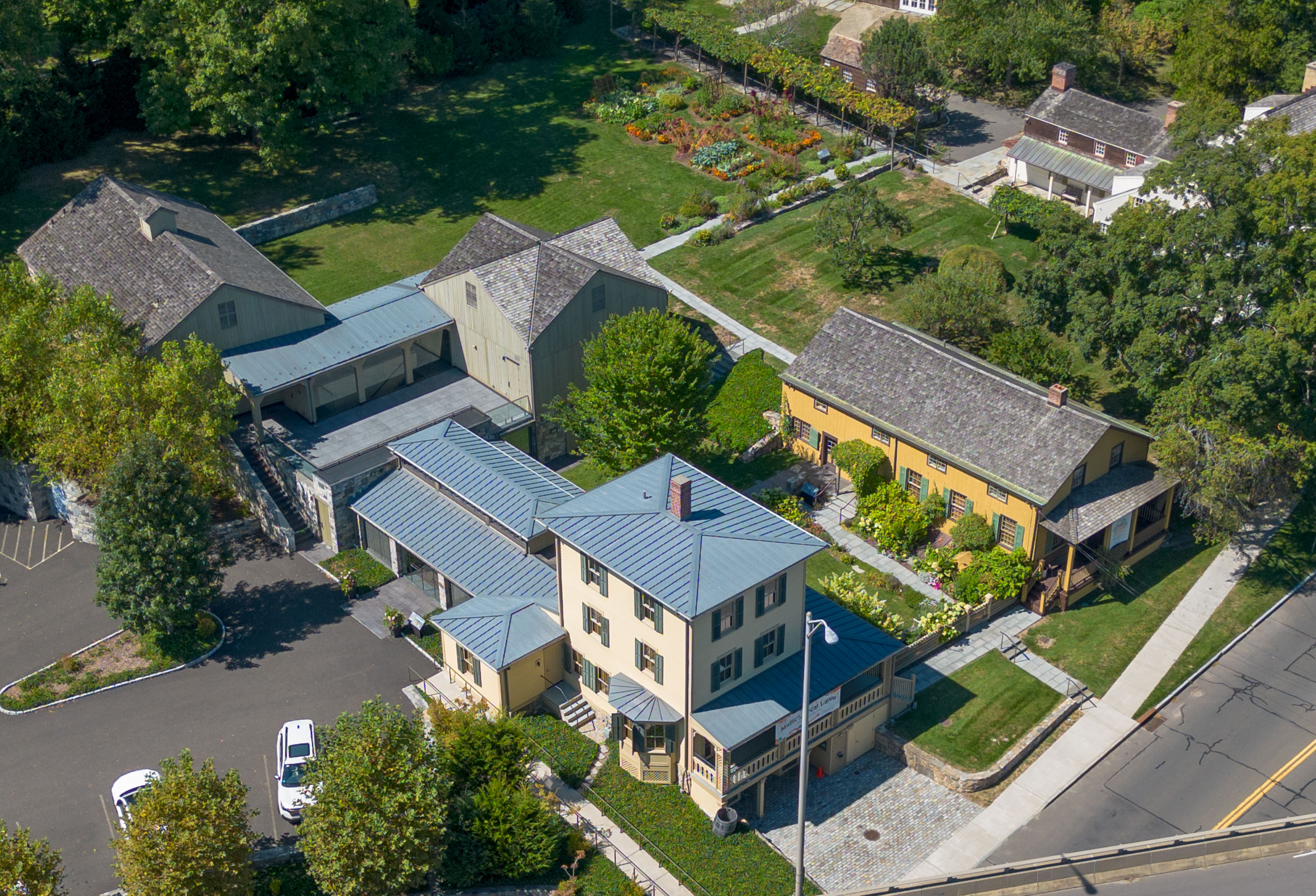 Aerial view of a historic building complex with gardens and surrounding trees.