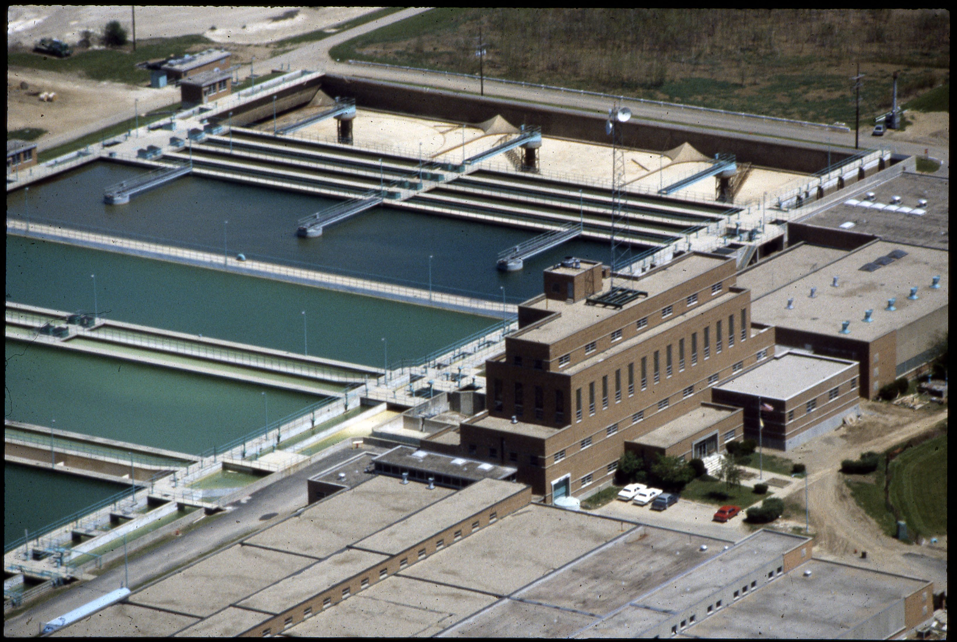 Aerial view of a water treatment plant with rectangular basins and a brick operations building.