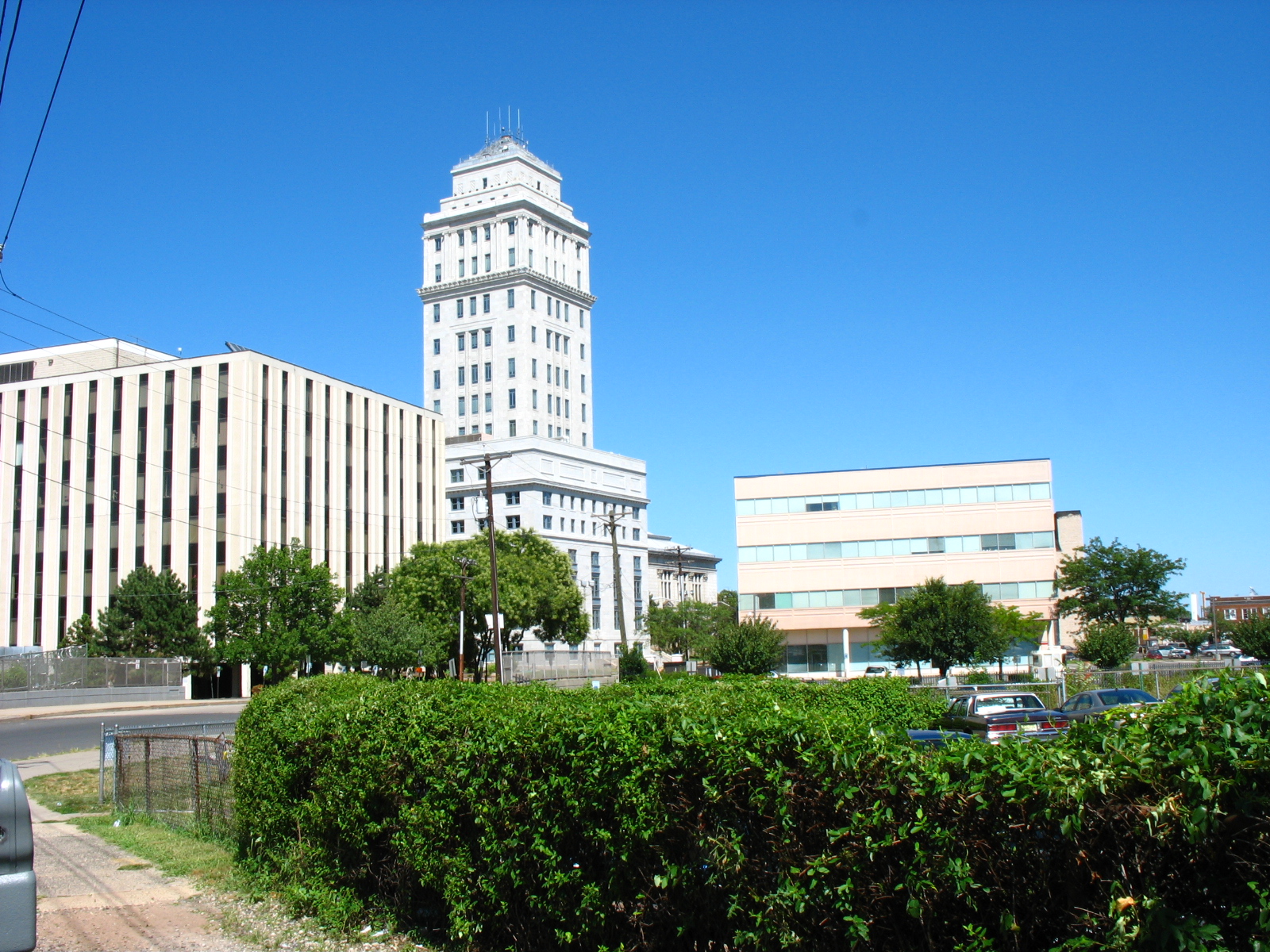 A tall white historic courthouse building with a clock tower flanked by modern office buildings.