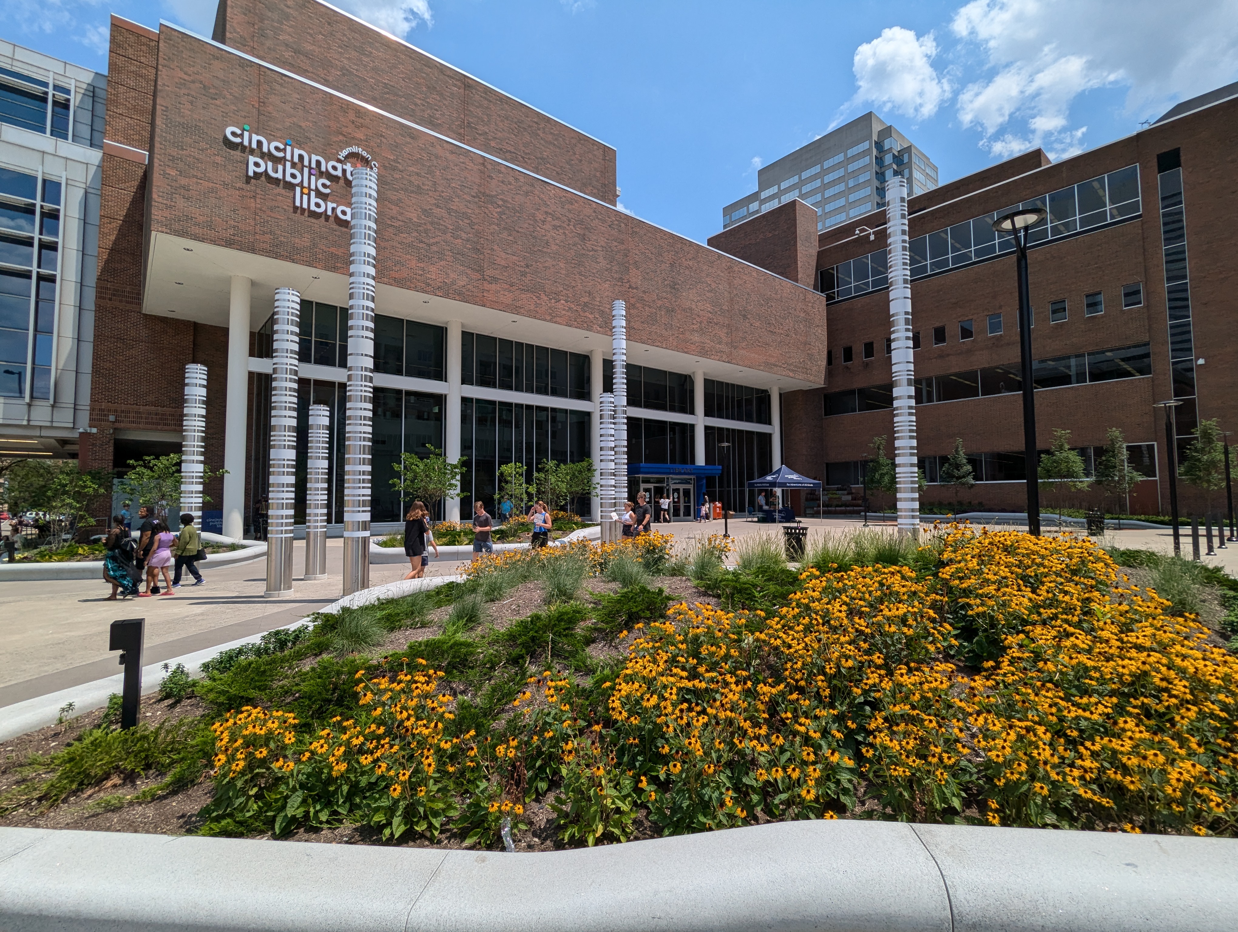 Brick library building with white columns and yellow flower beds out front.