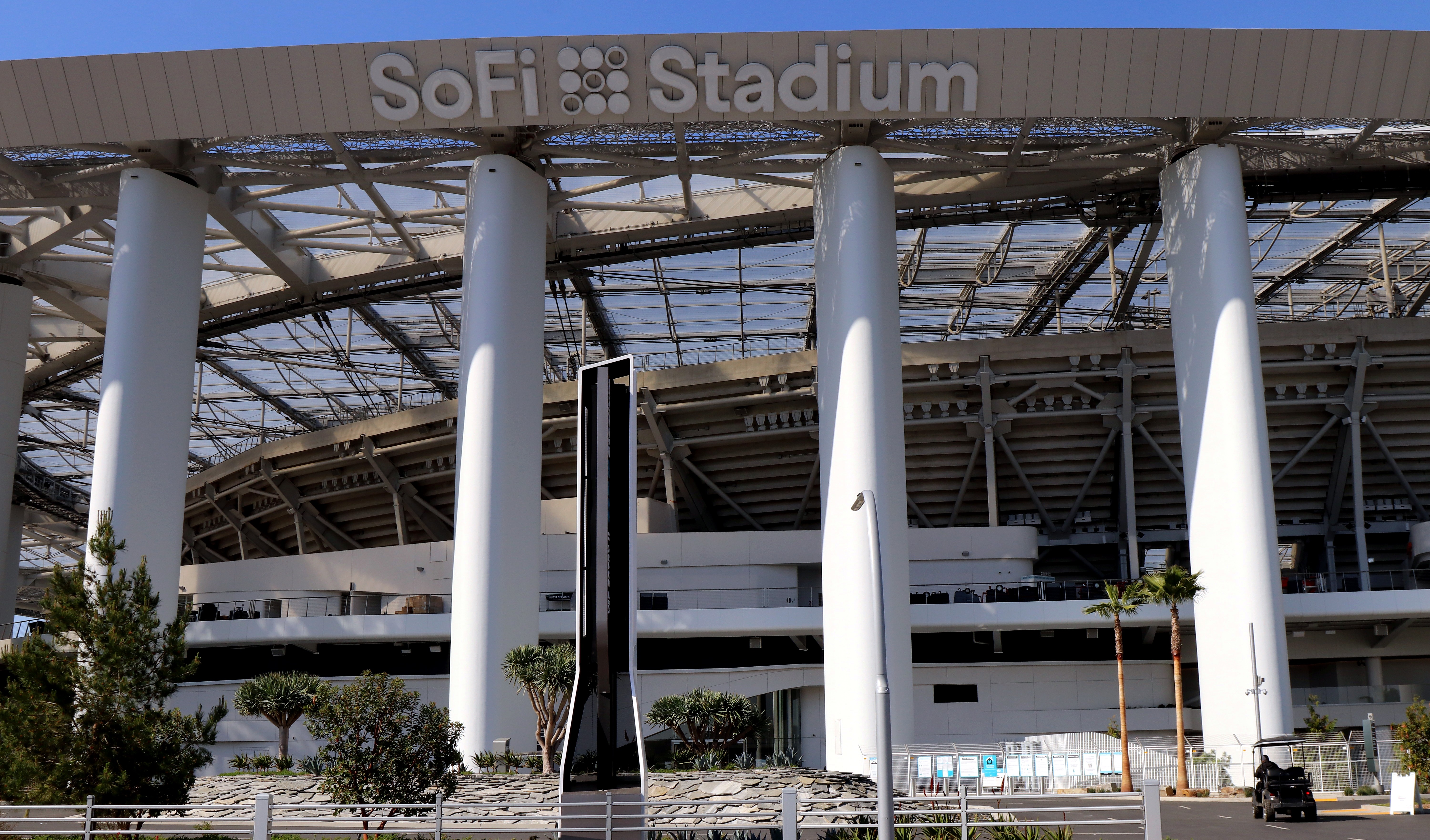 Exterior of a large modern stadium with white columns and a translucent roof canopy.