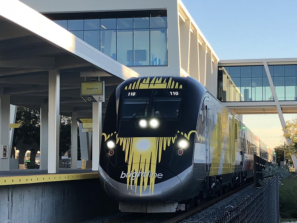 Brightline passenger train with black-and-yellow livery at a covered station platform.