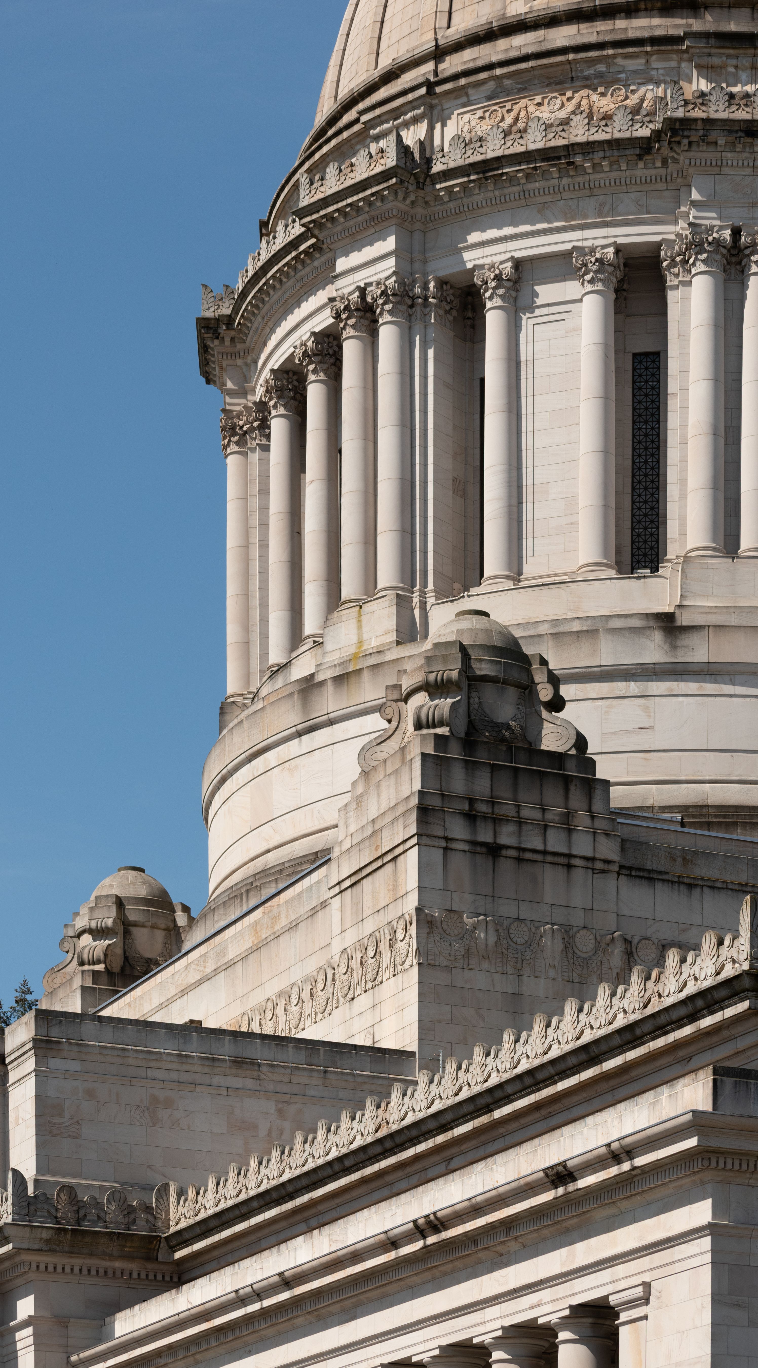 Dome and Corinthian columns of the Washington State Capitol building against a blue sky.