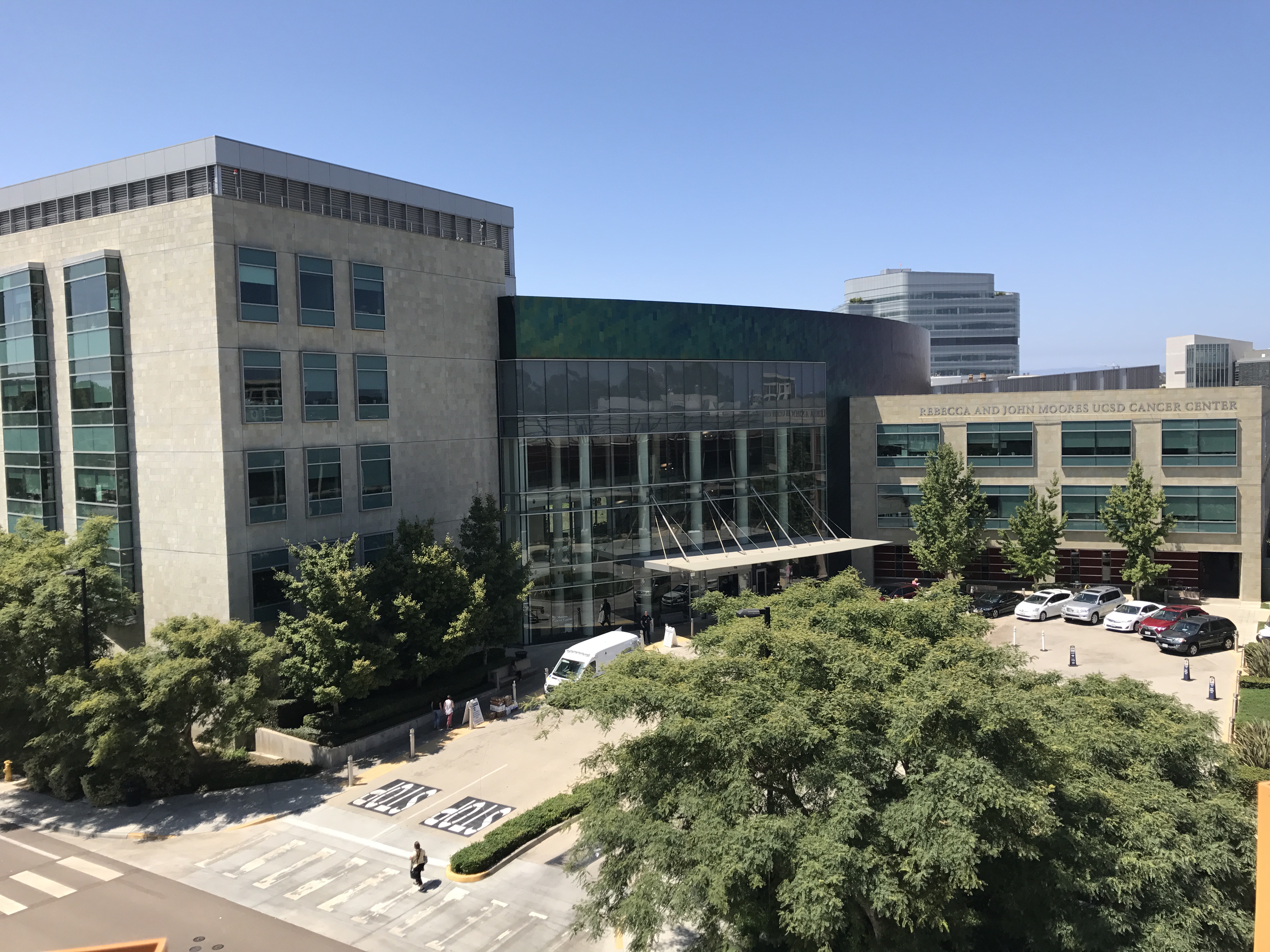 Aerial exterior view of a multi-story medical building surrounded by trees on a sunny day.