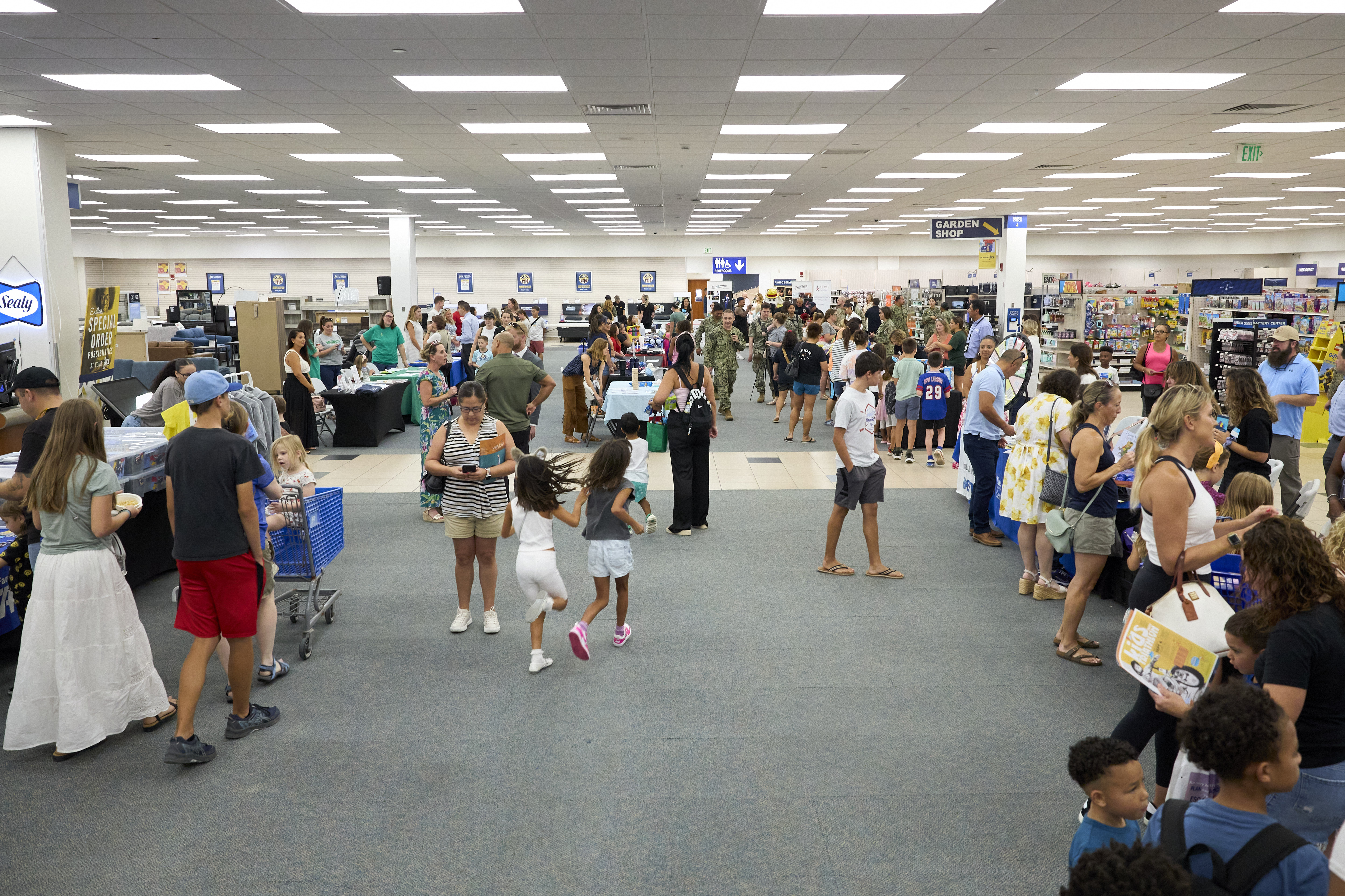 Families and children browse vendor booths at an indoor back-to-school community fair.