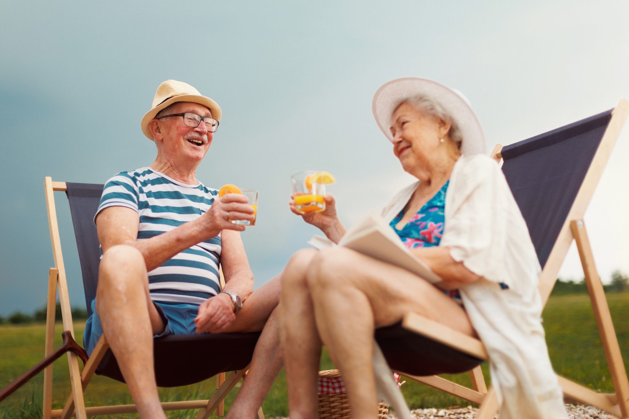 Senior couple enjoying summer time, sitting on deck chairs near water.