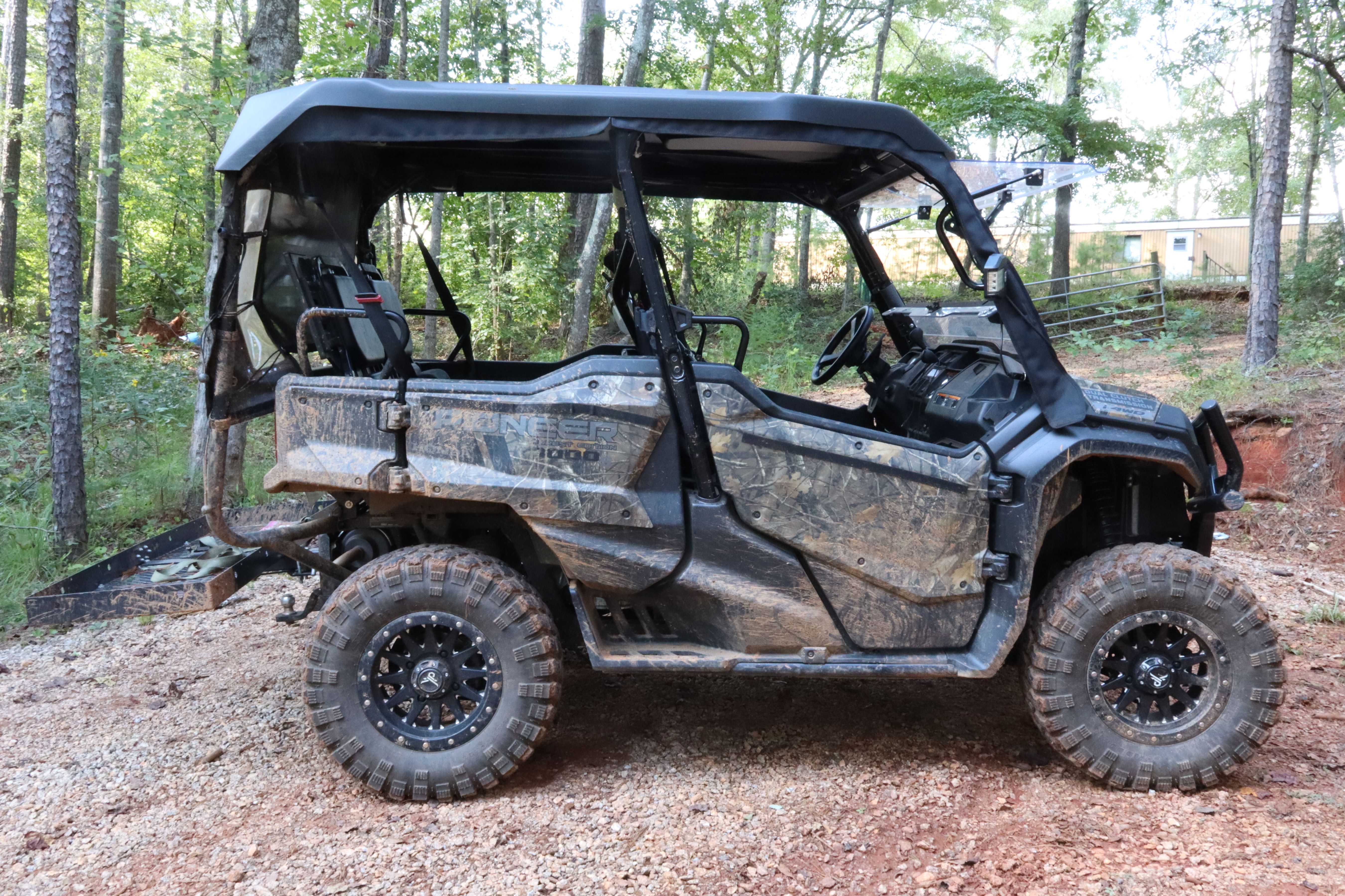 A camouflage-patterned side-by-side UTV with a roll cage parked outdoors.
