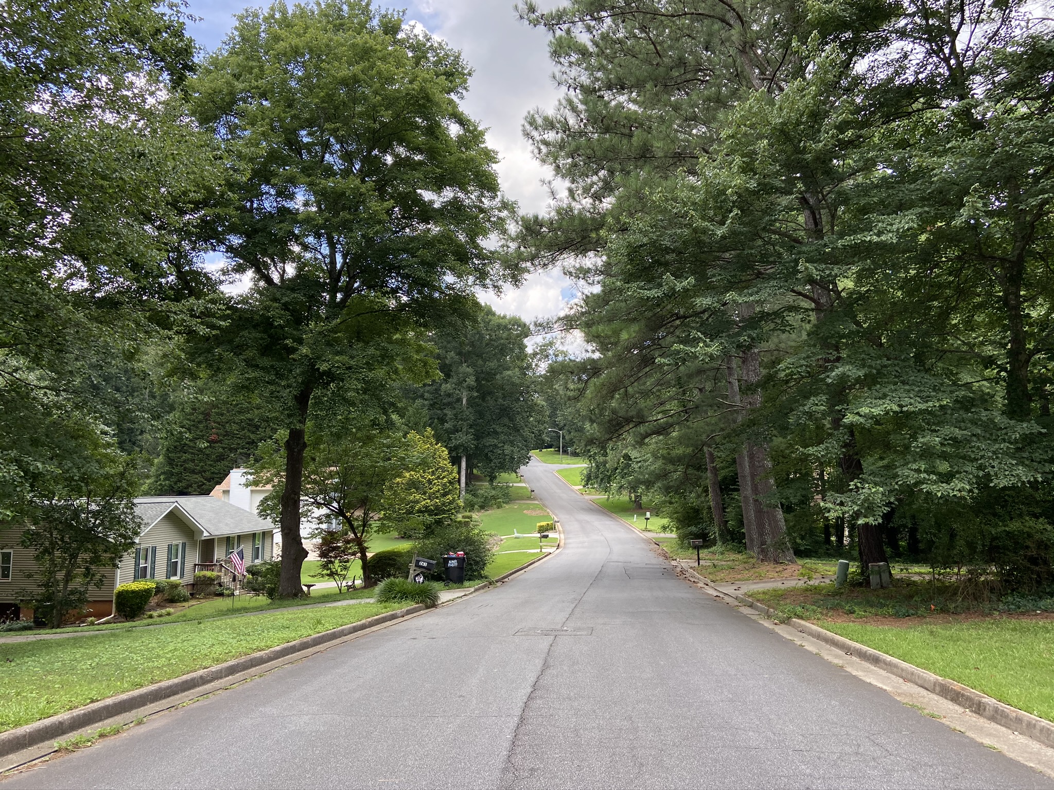 A paved two-lane road winds through a residential neighborhood in Mableton, Georgia.