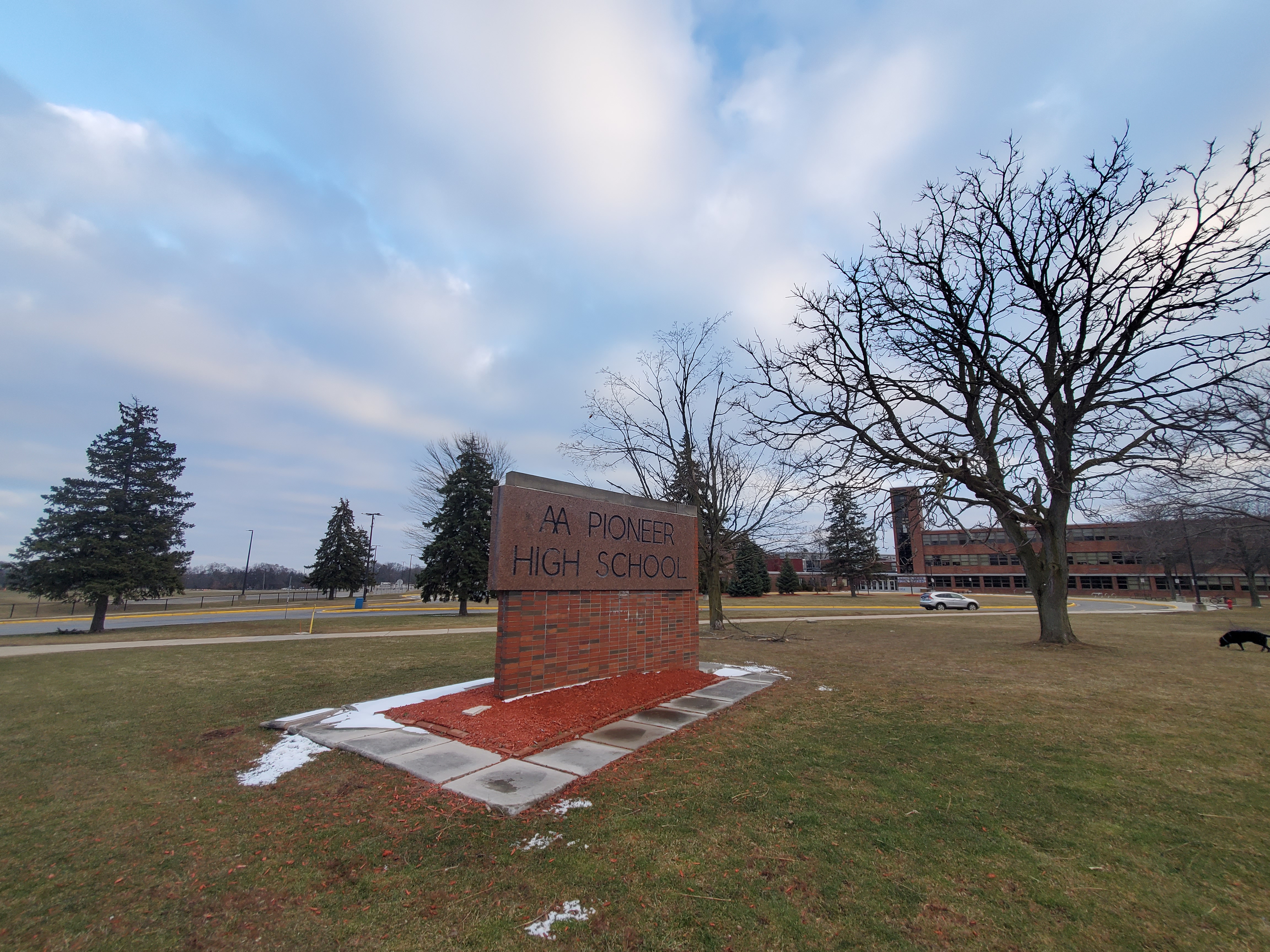Brick monument sign for Pioneer High School on a snowy campus lawn.