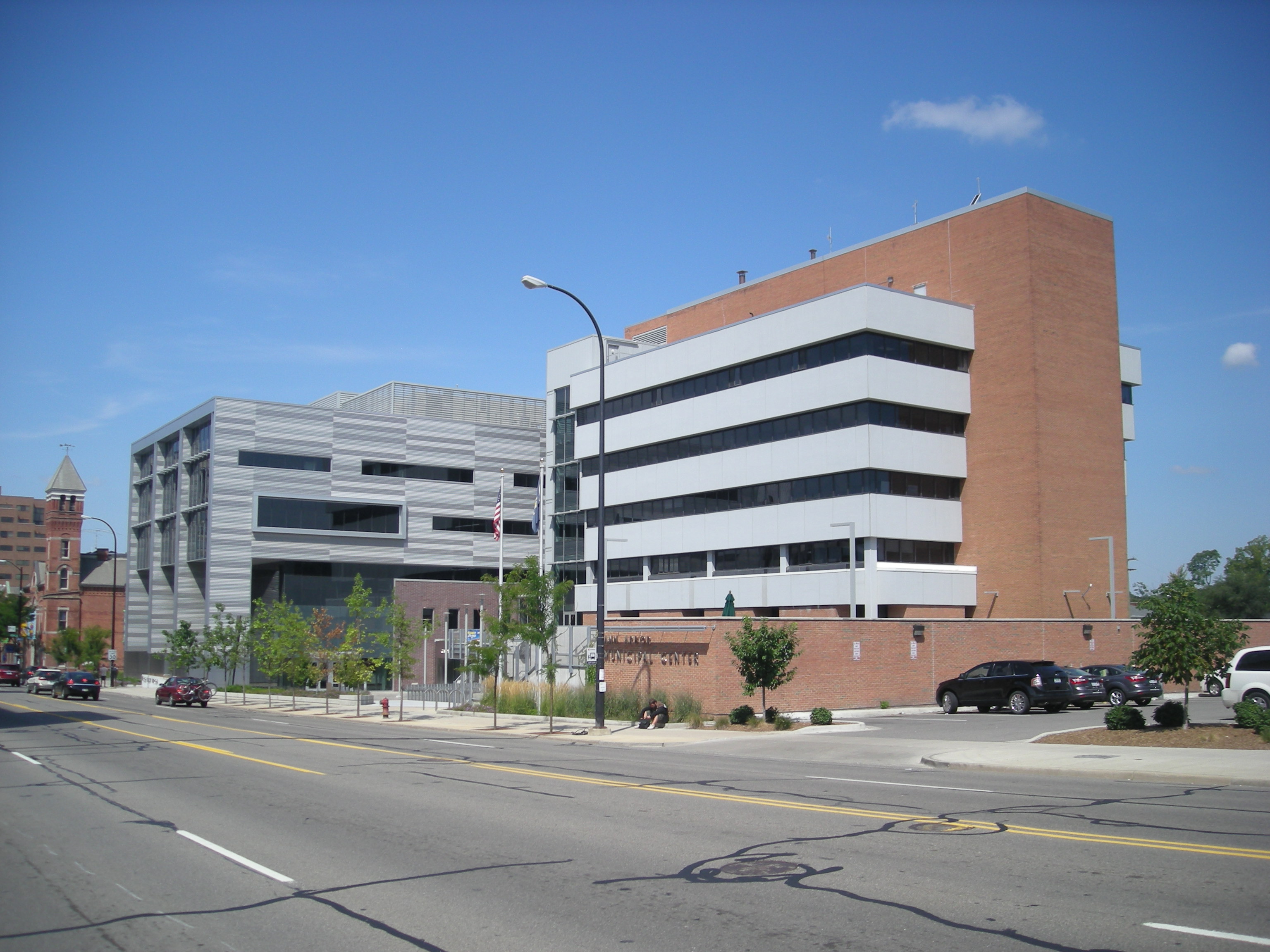 Multi-story municipal building with brick and metal panel facade, a street lamp in the foreground.