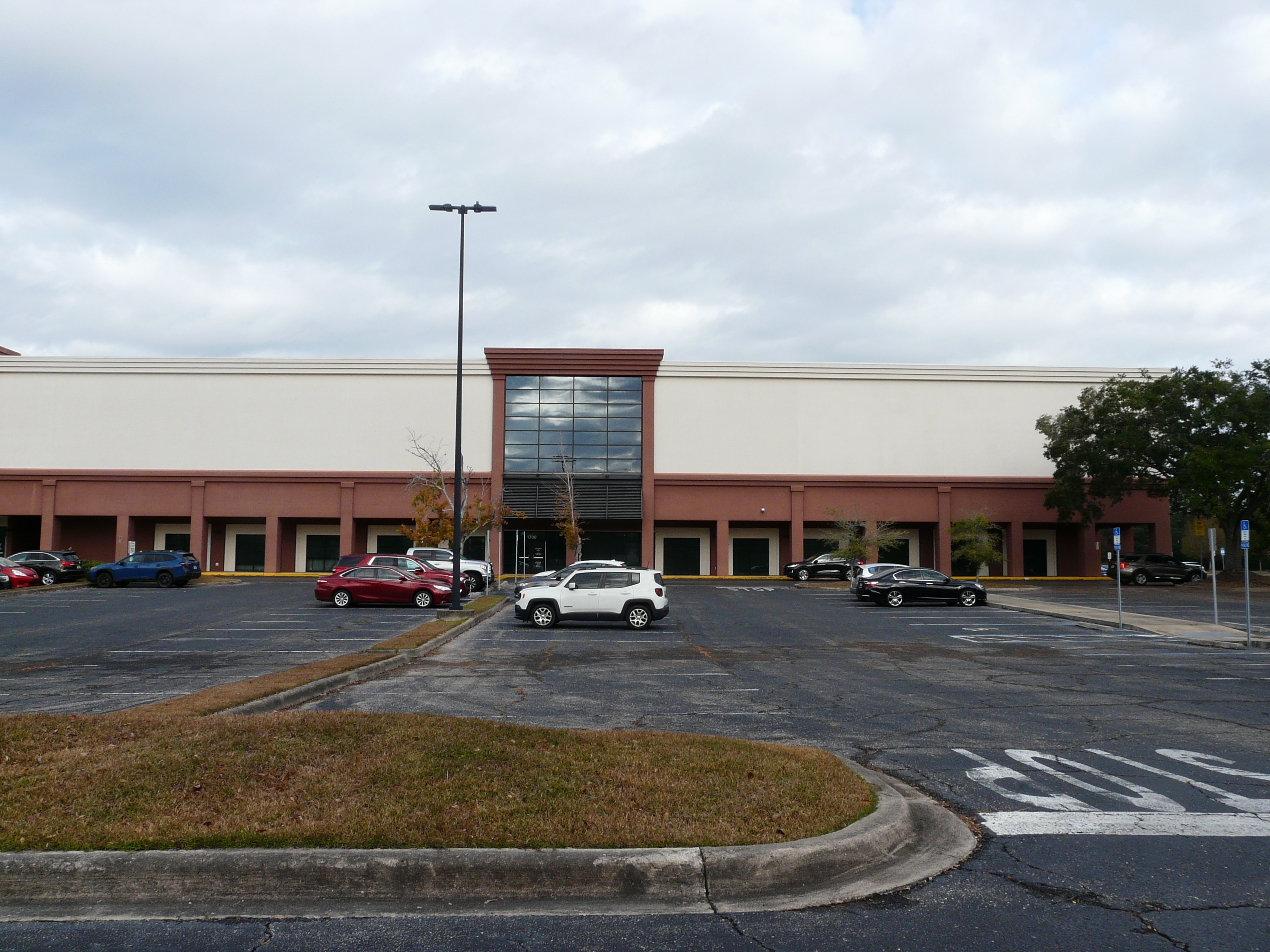 Large commercial building housing Florida Department of Health offices, with a glass entrance and parking lot.