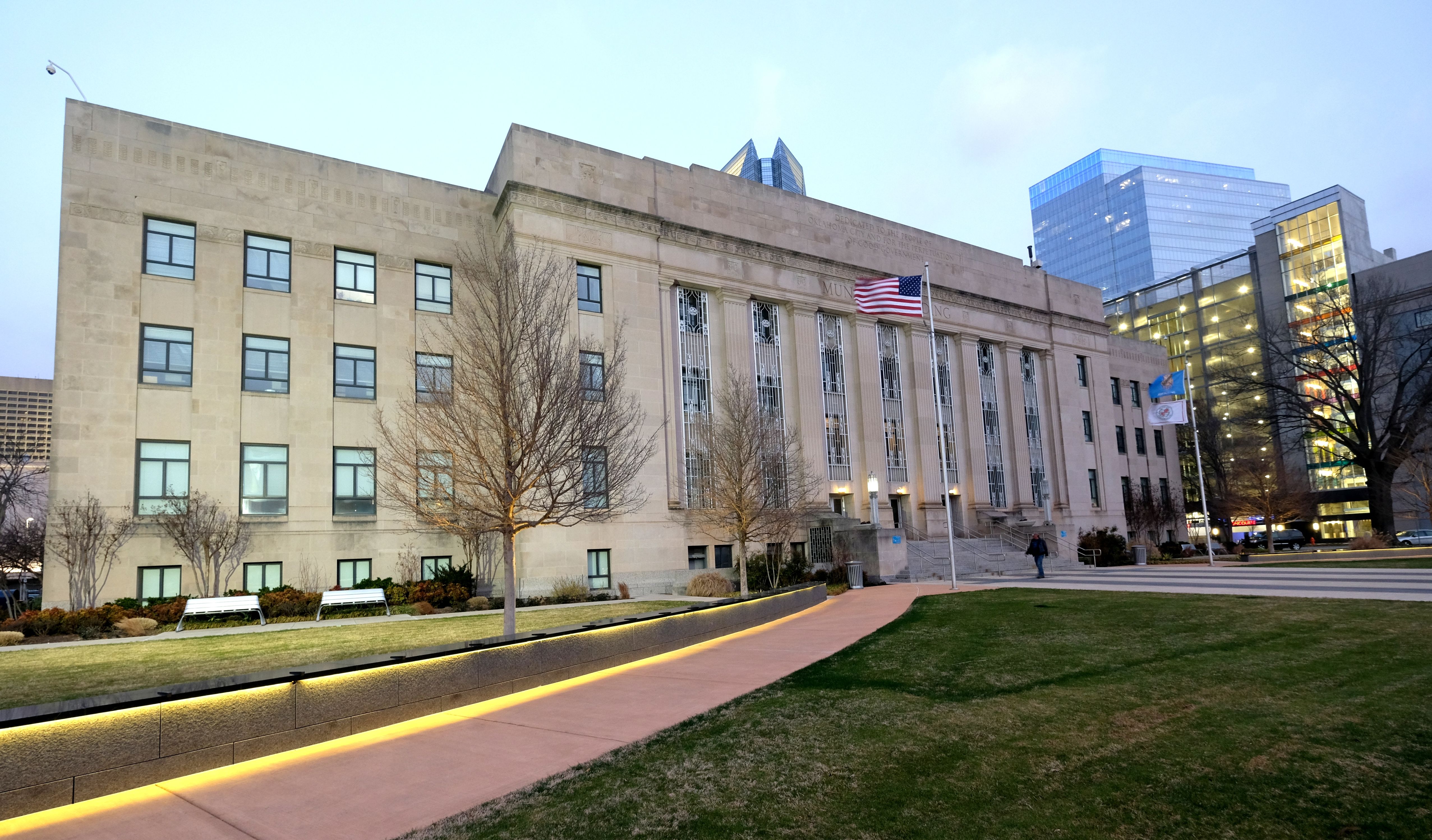 Art Deco Oklahoma City Municipal Building with flags on flagpoles at dusk.