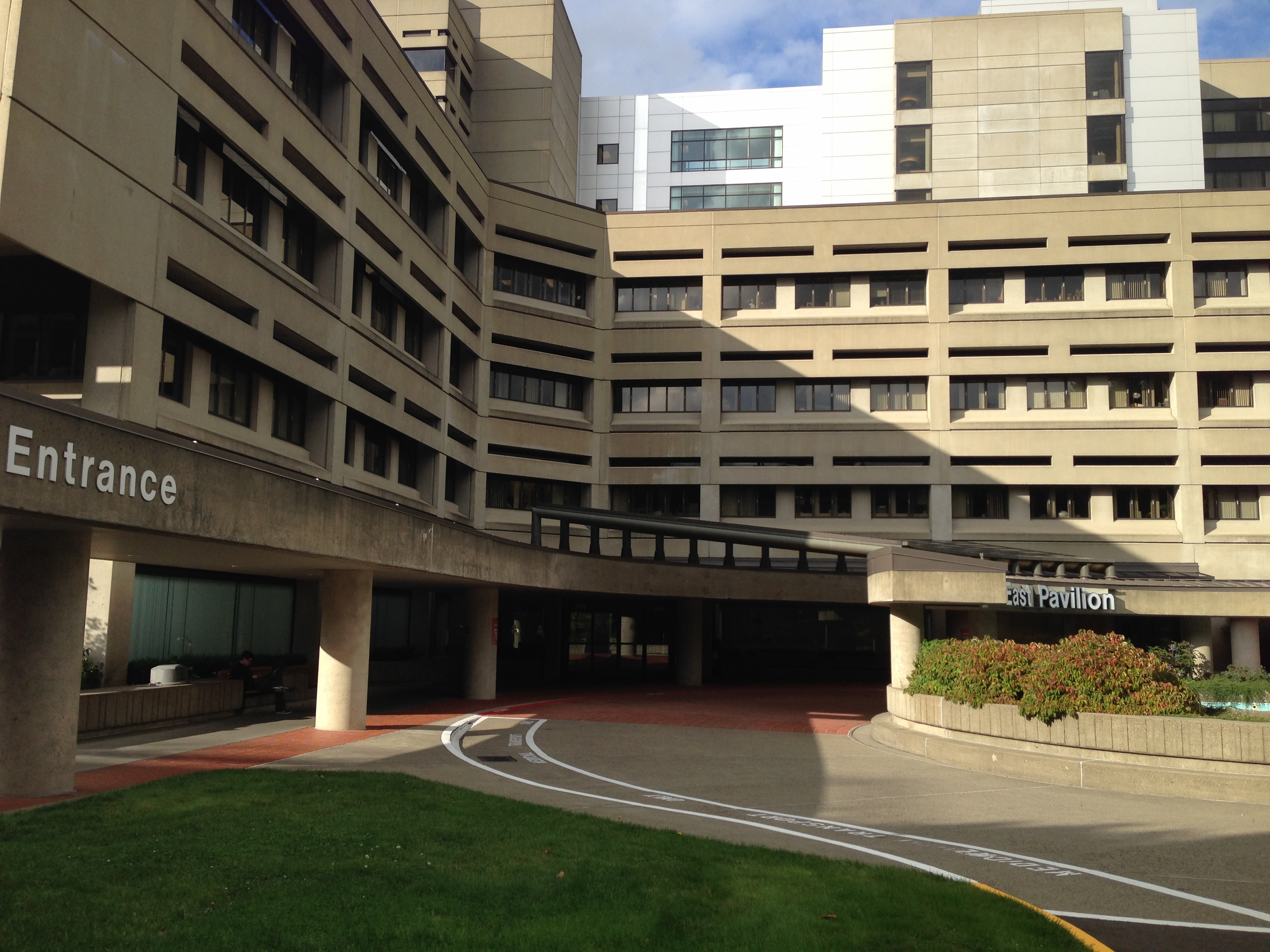 Large multi-story hospital building with curved entrance driveway and East Pavilion sign.
