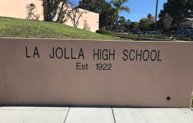 Concrete wall reading 'La Jolla High School Est. 1922' with a grassy hillside behind it.
