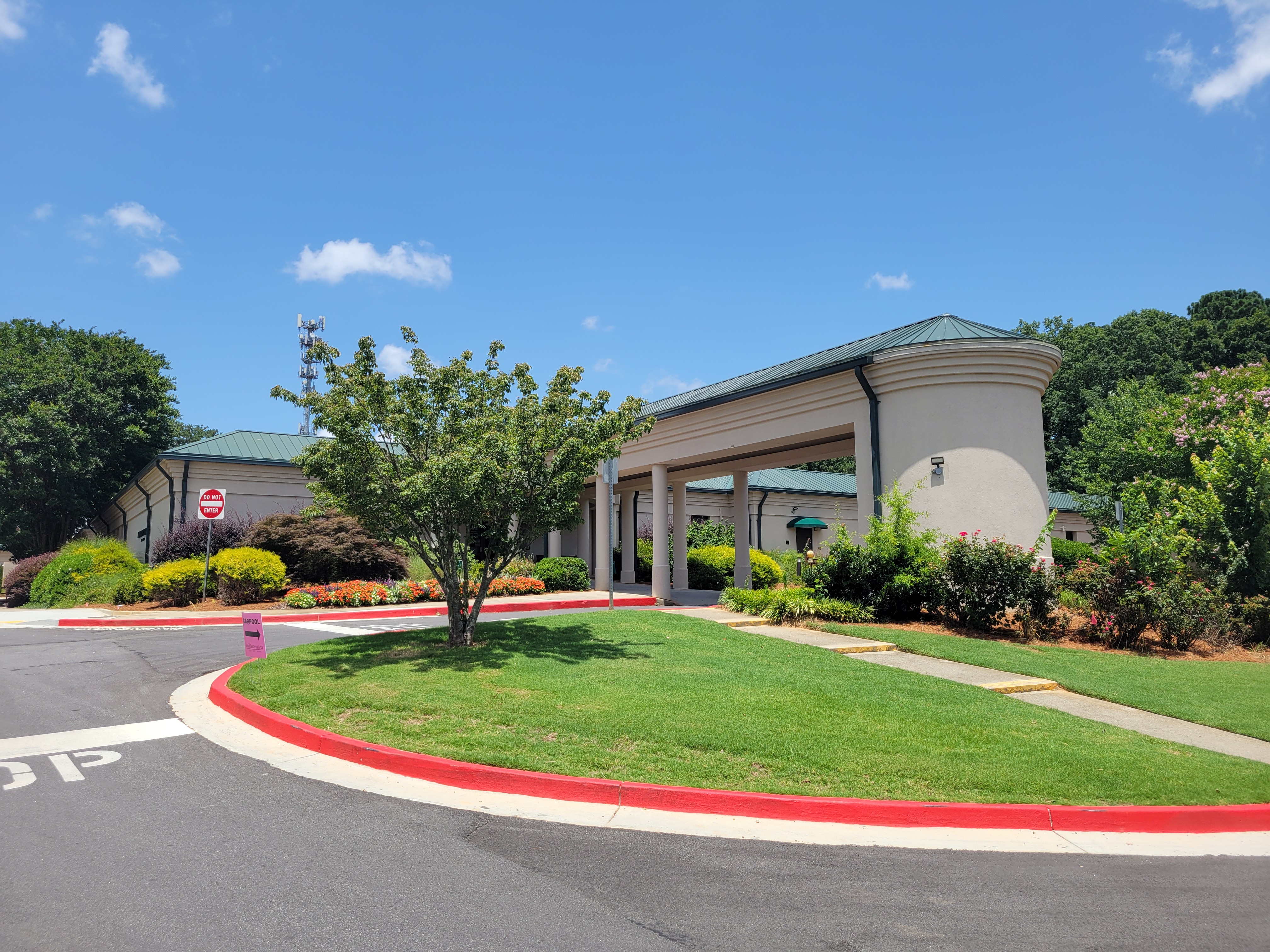 Single-story public library building with green roof, columned entrance, and manicured landscaping.
