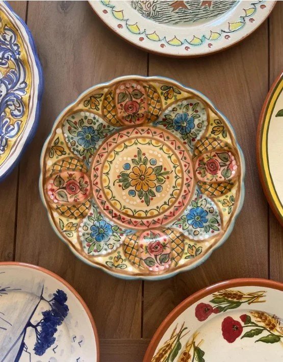 Several colorful hand-painted ceramic plates displayed on a wooden surface.