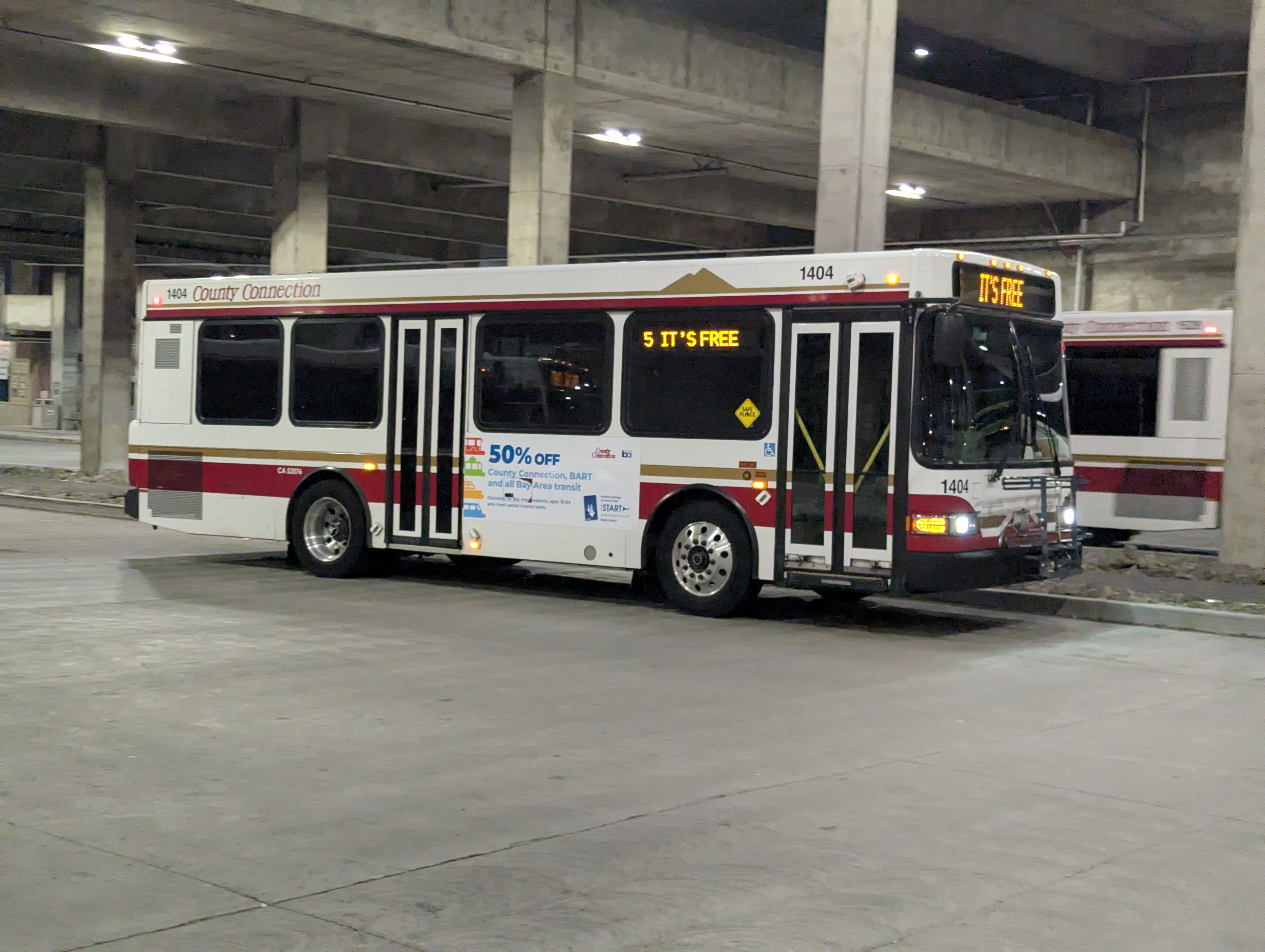 A County Connection bus with 'IT'S FREE' on its destination sign at a covered transit bay.
