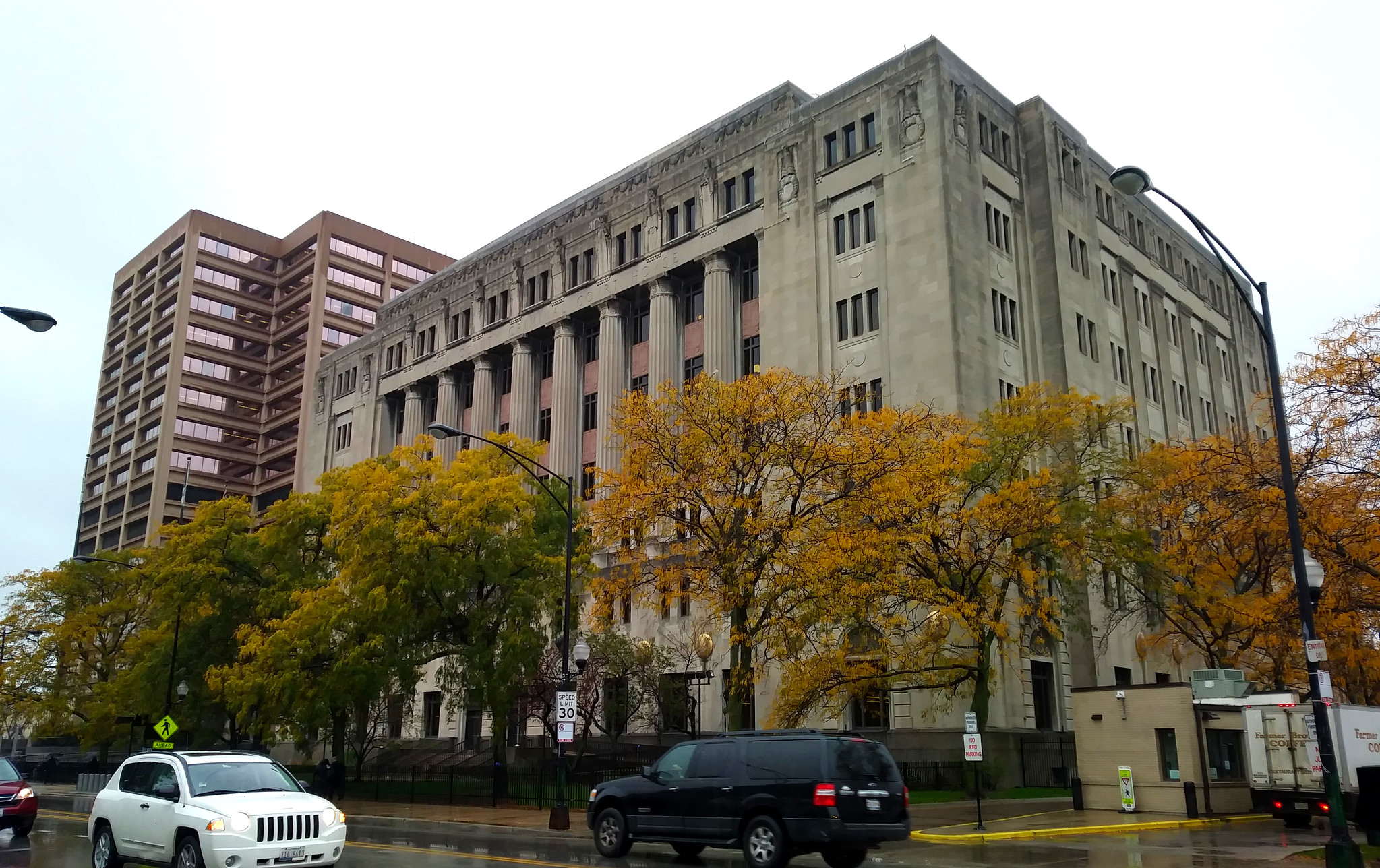 Neoclassical courthouse building with columns and autumn trees lining the sidewalk.