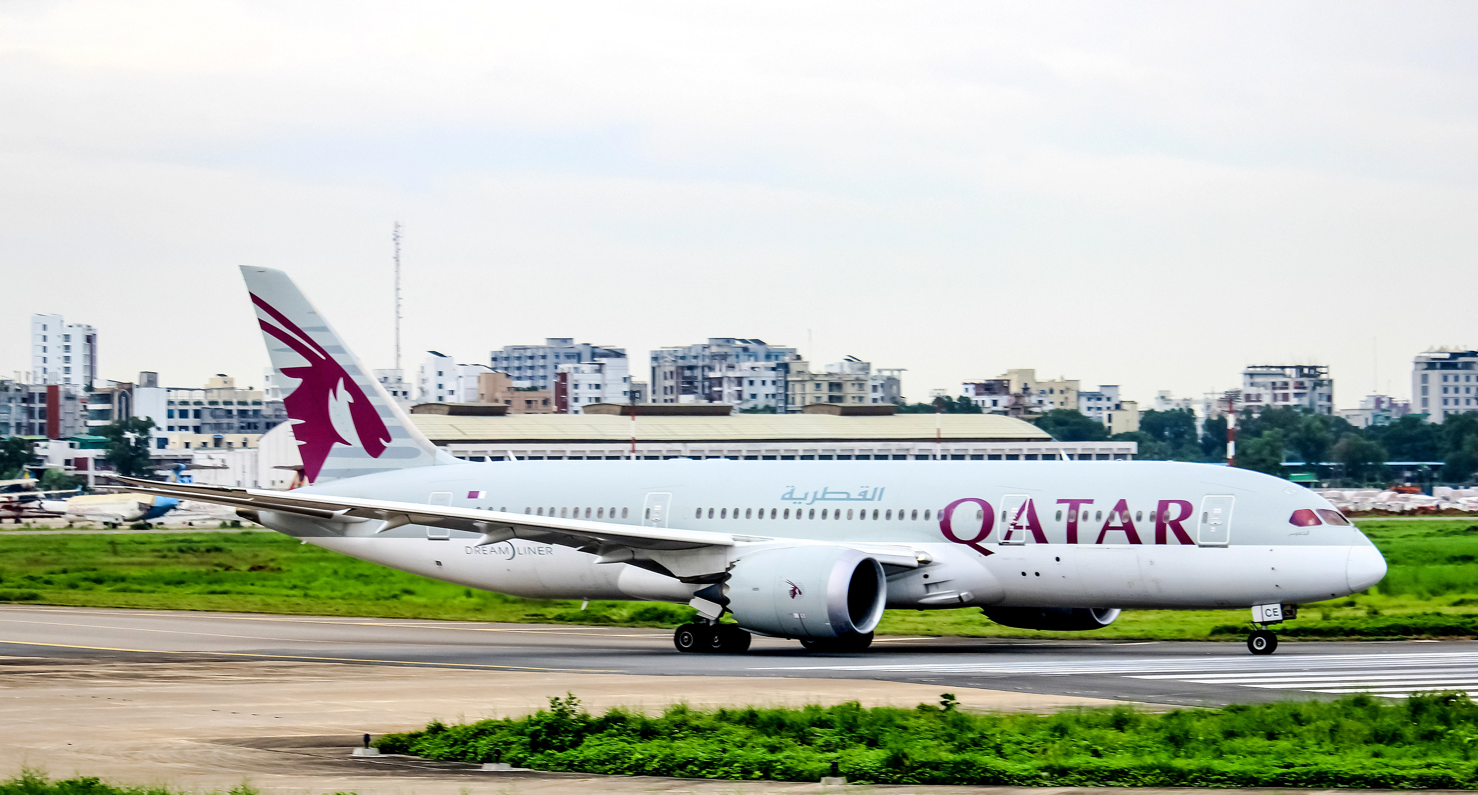 A white wide-body jetliner with maroon airline markings taxiing on a runway.