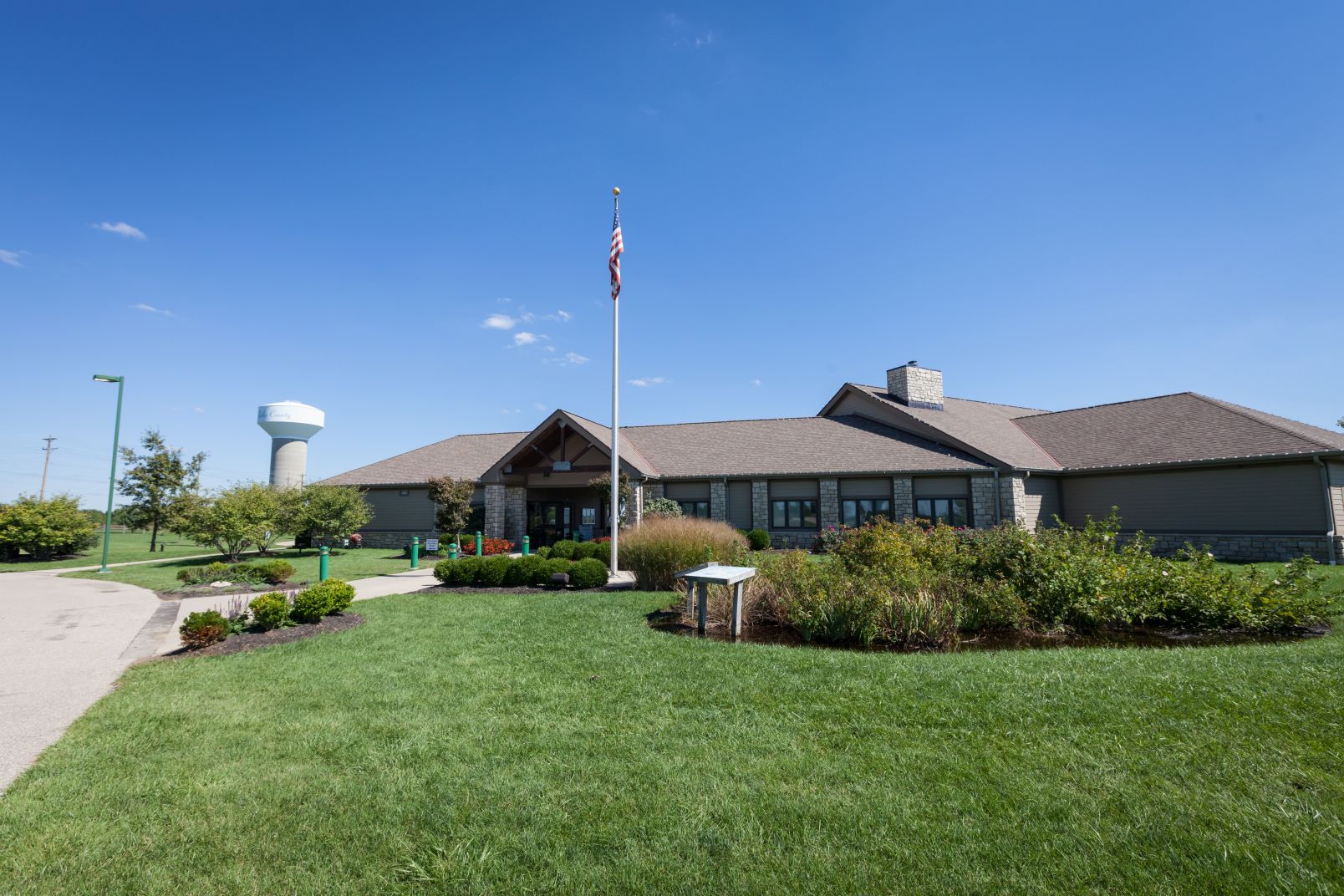 Stone and siding lodge building with American flag and water tower in background.