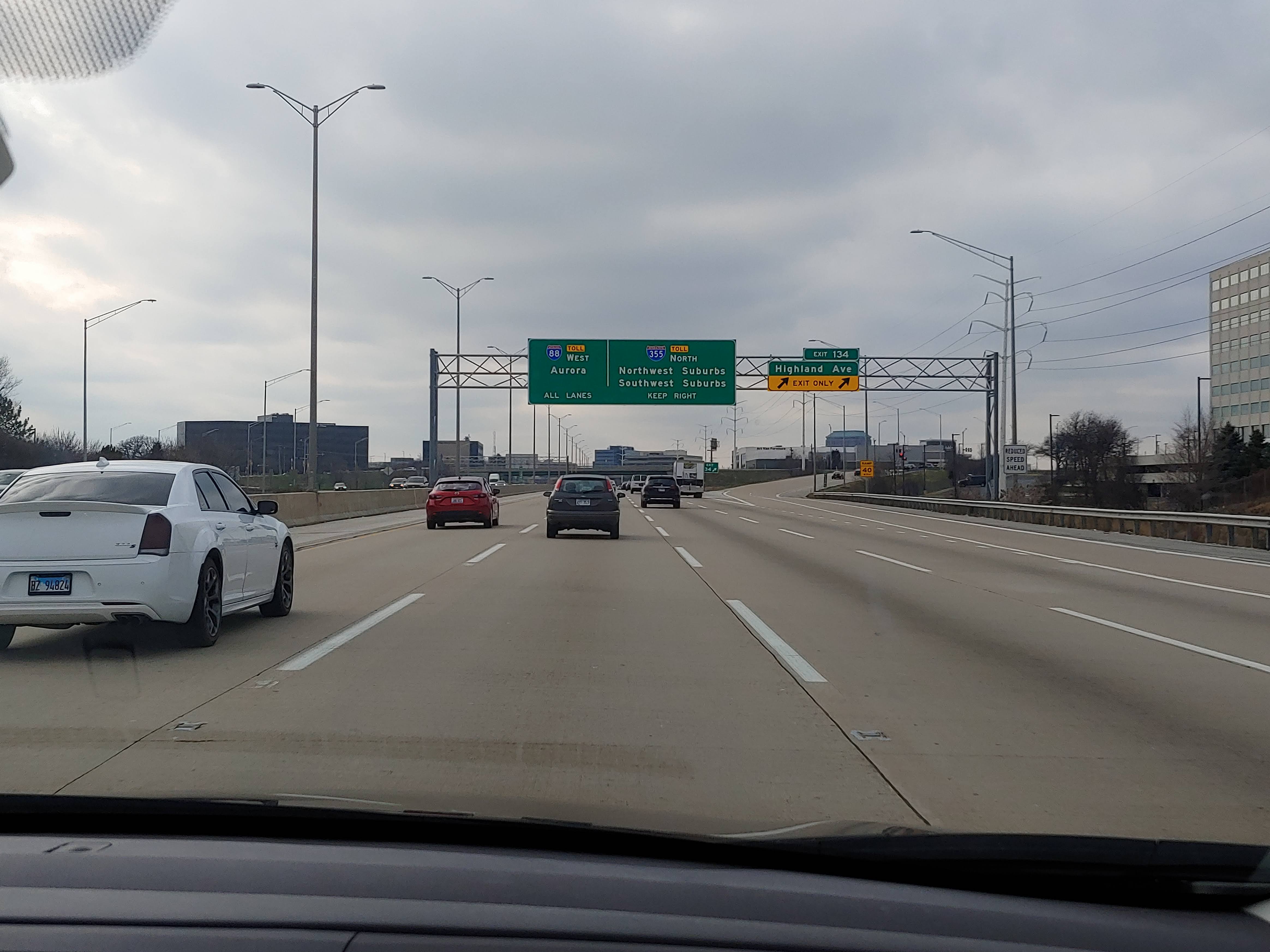 Multi-lane highway with overhead green signs pointing to Aurora and I-355.