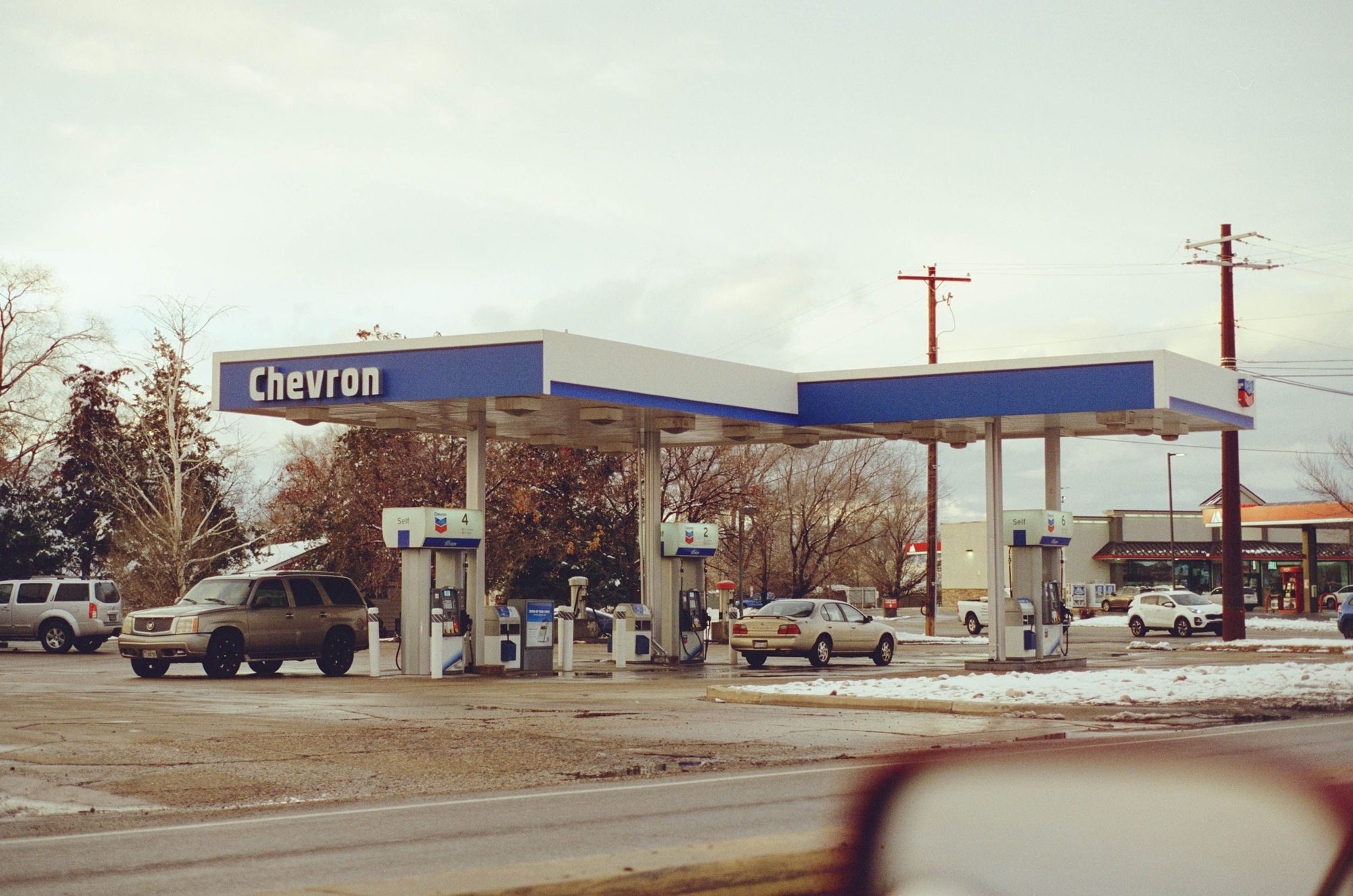 A Chevron gas station with several vehicles parked.