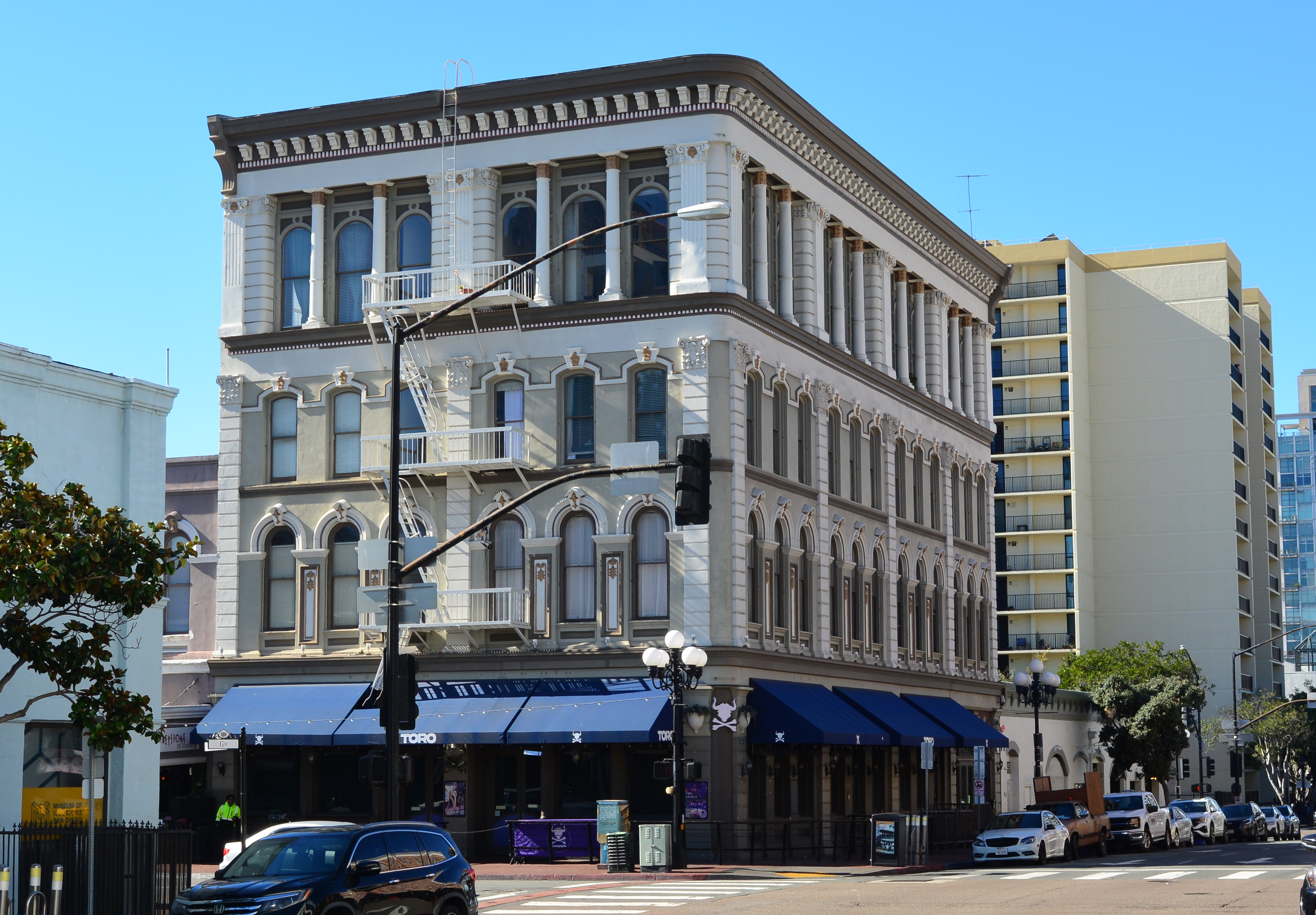 Ornate Victorian-era building on a downtown San Diego street corner with blue awnings
