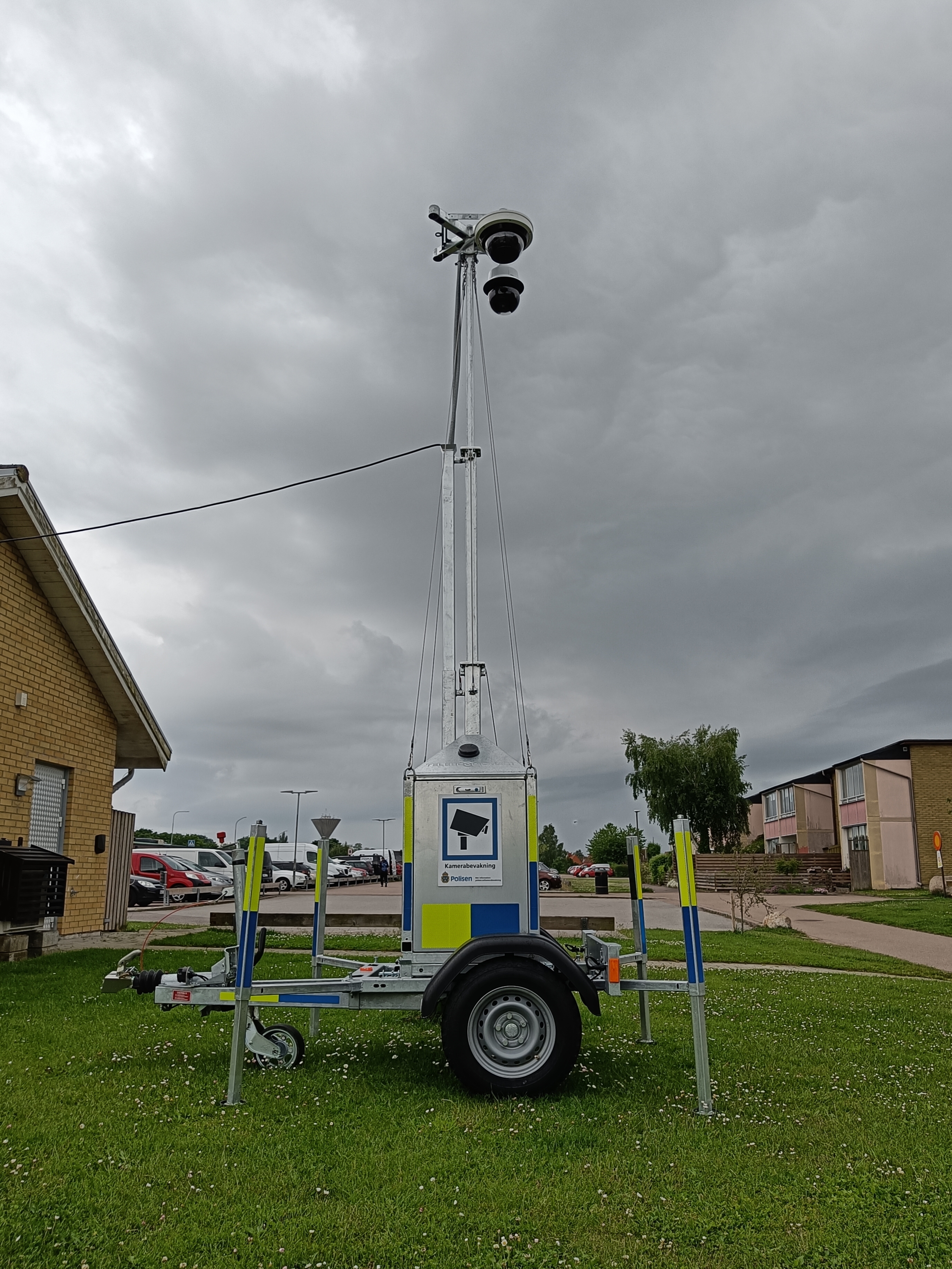 Mobile surveillance tower with dome cameras on an extendable mast mounted on a trailer.