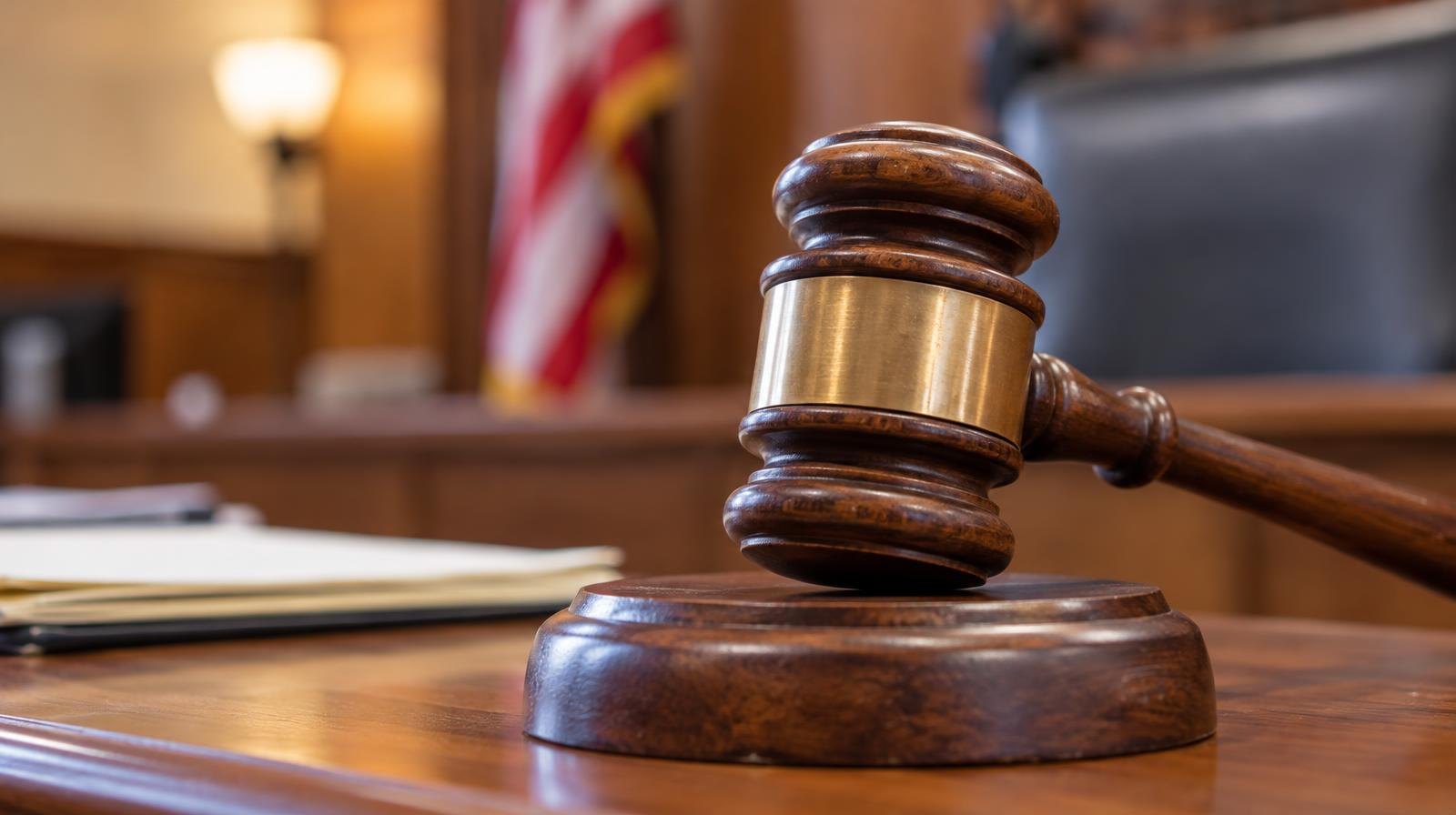 A wooden gavel resting on its sound block on a courtroom bench.