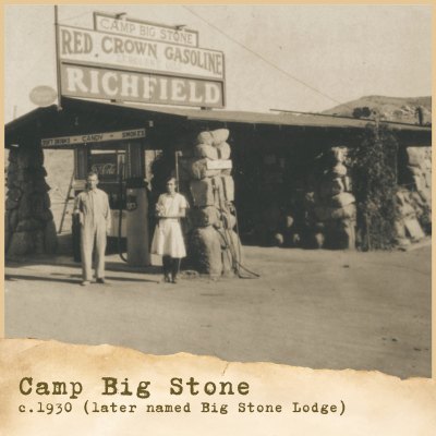 Vintage sepia photo of a stone-and-timber building with two people standing outside.
