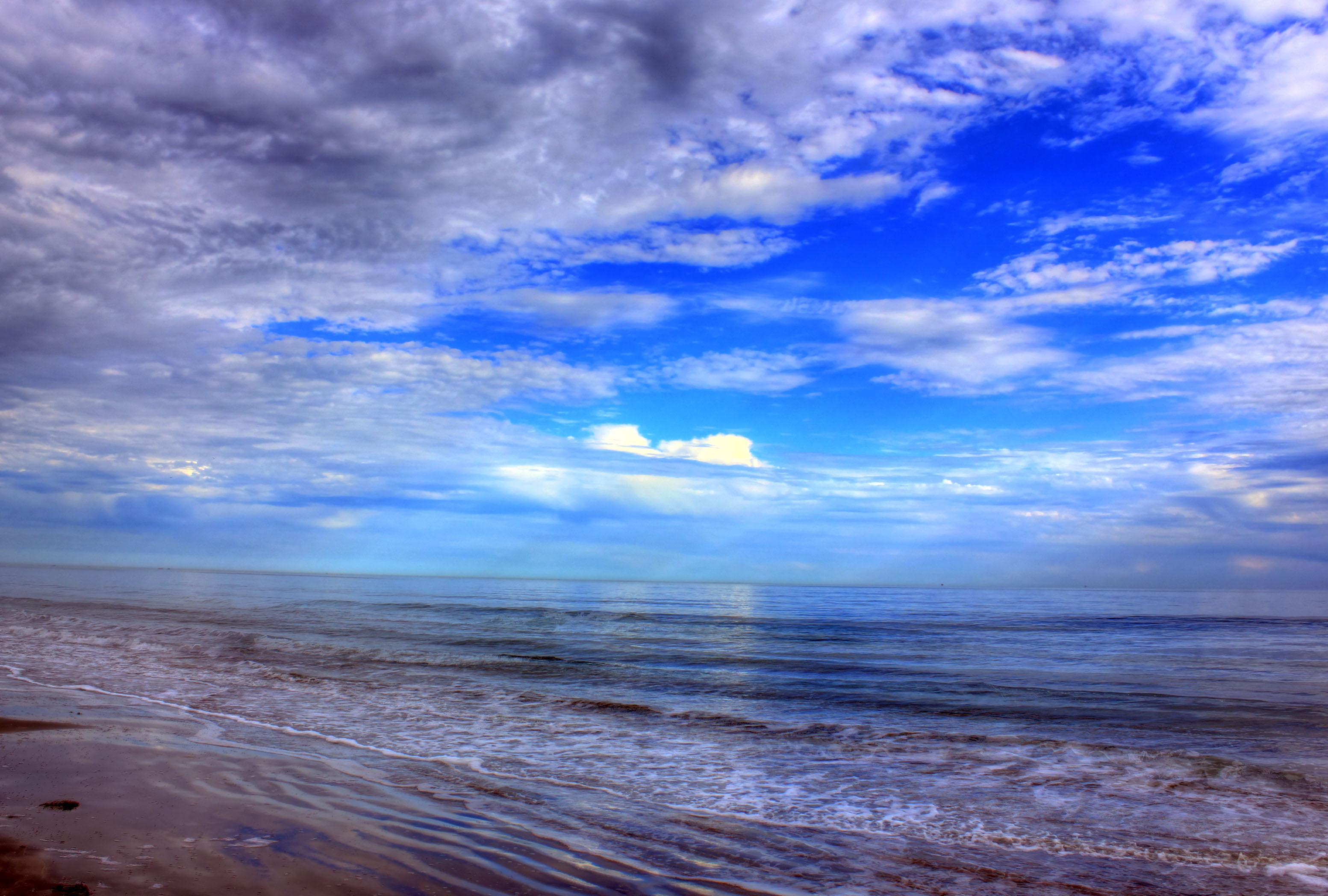 Sandy beach and Gulf of Mexico waters under a wide blue sky.