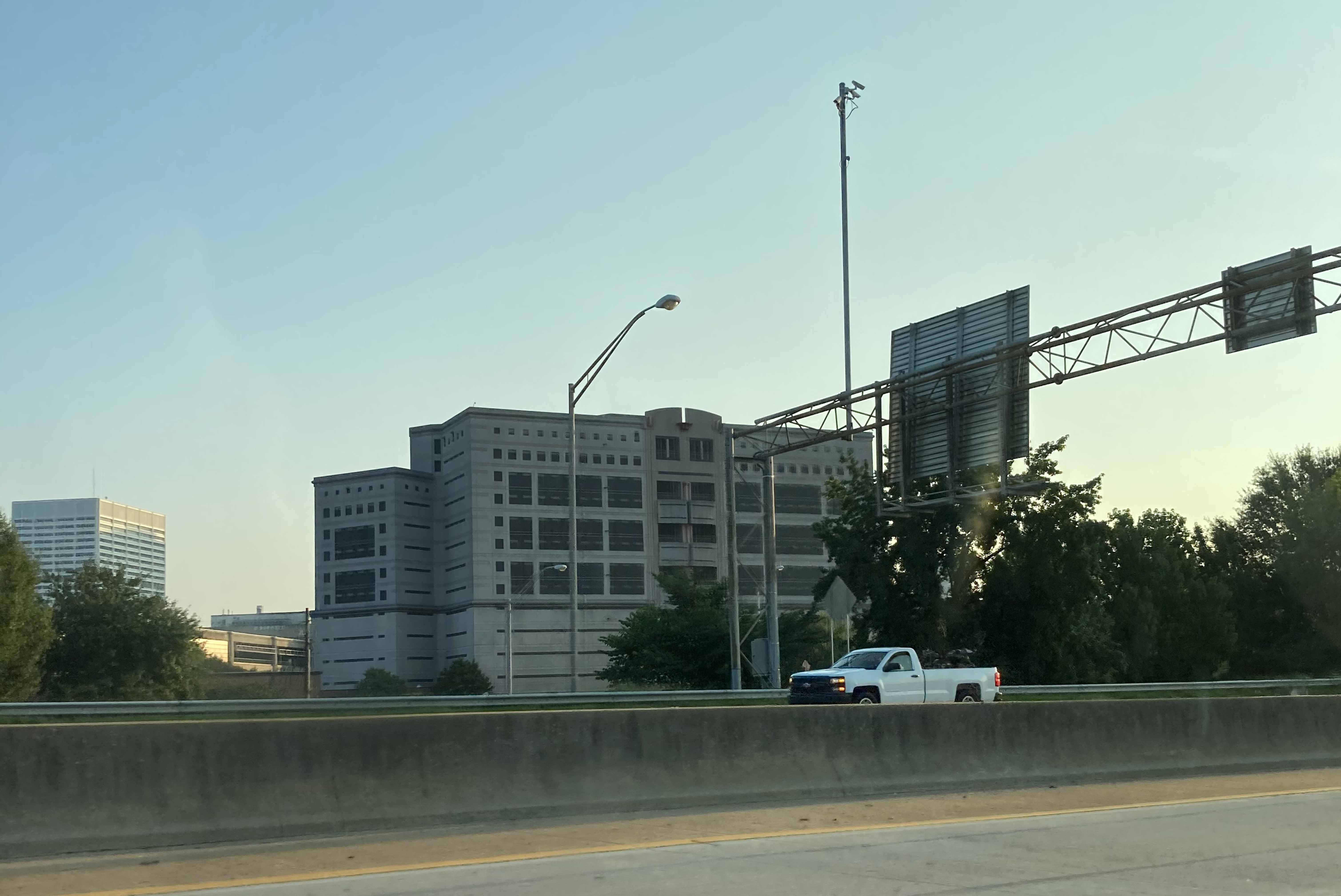Large multi-story concrete detention facility viewed from a highway.