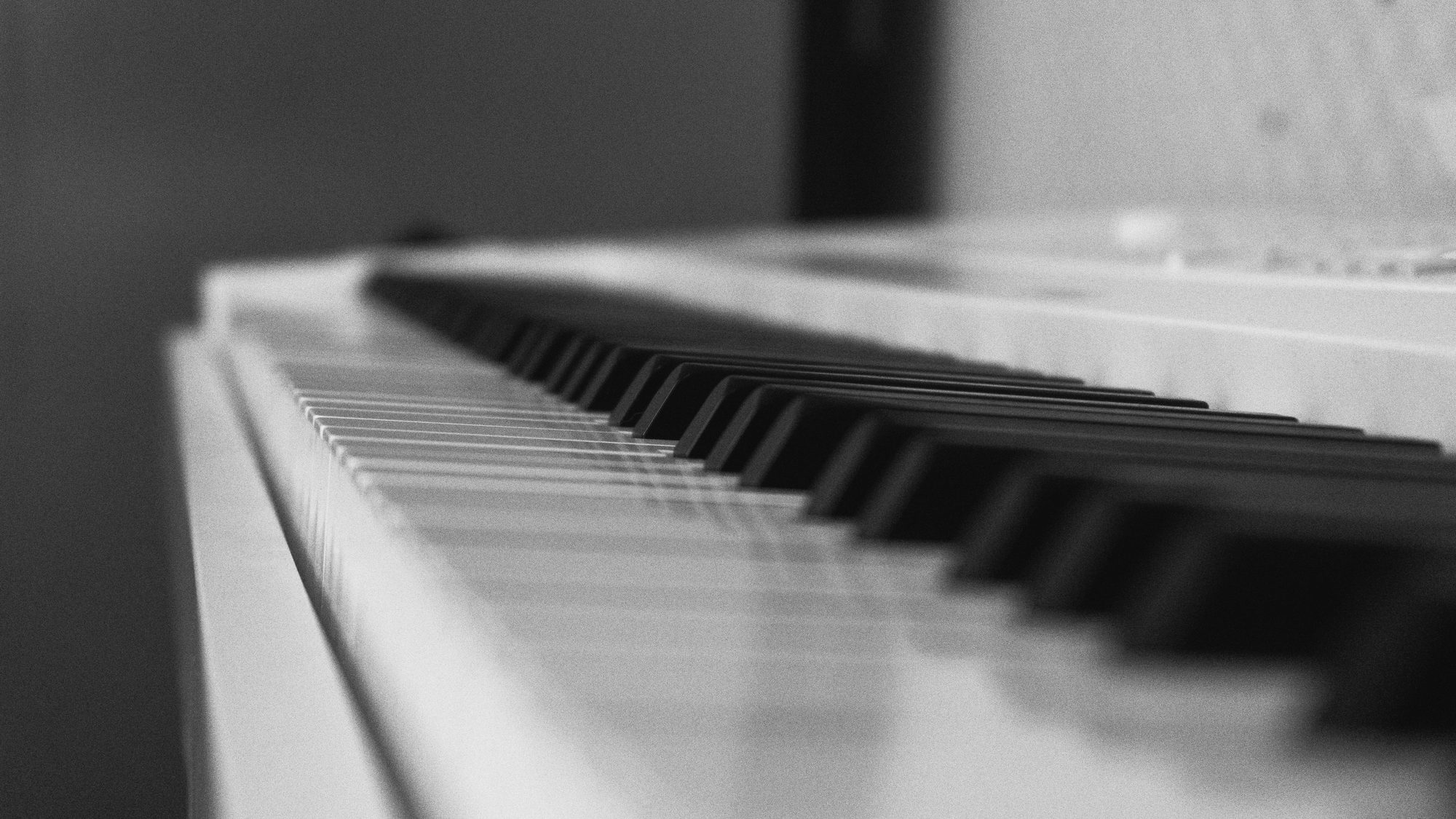 A black and white artistic close-up photograph of piano keys, emphasizing the textures and tones.