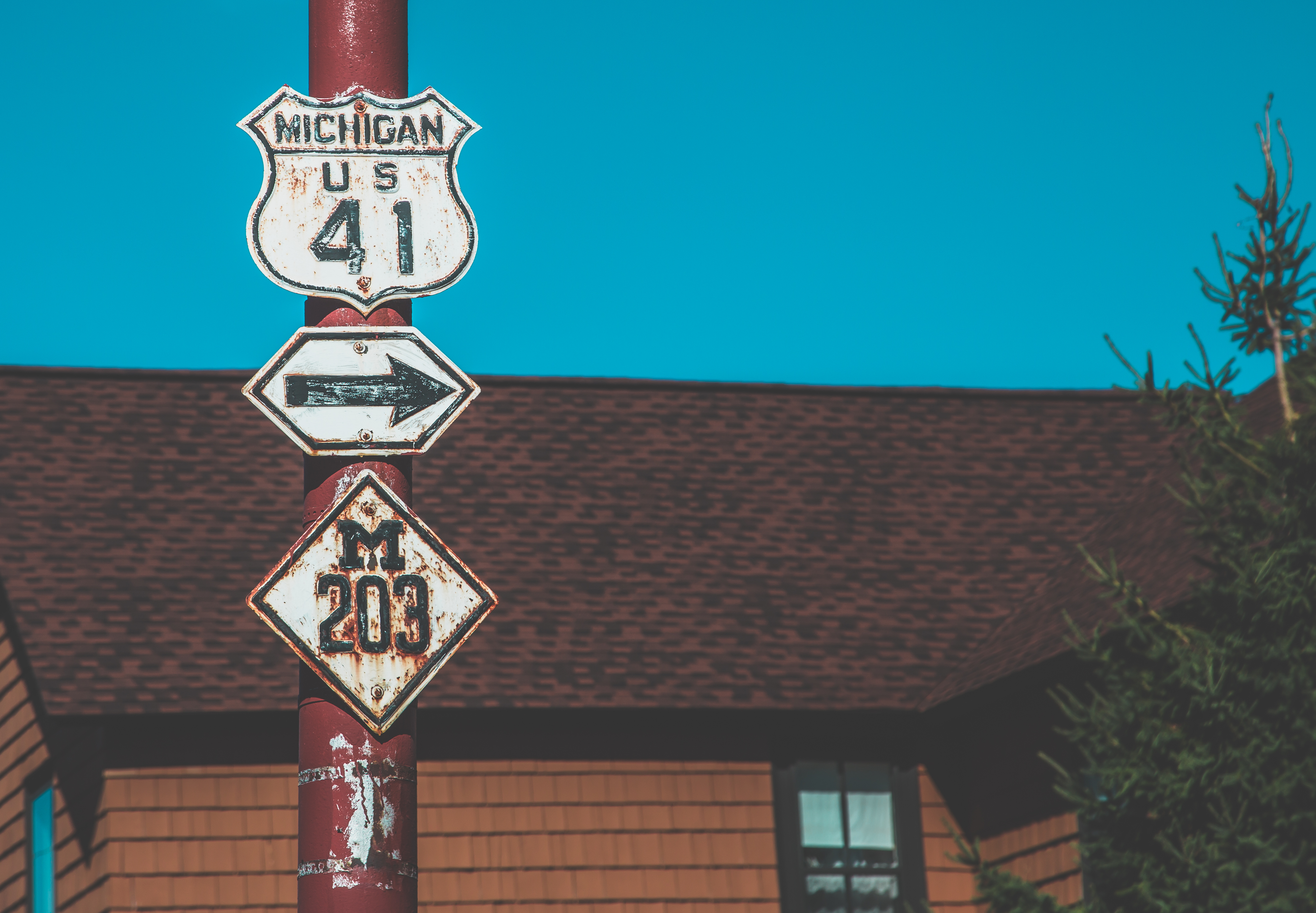 Weathered US-41 highway sign on a red pole against a blue sky.