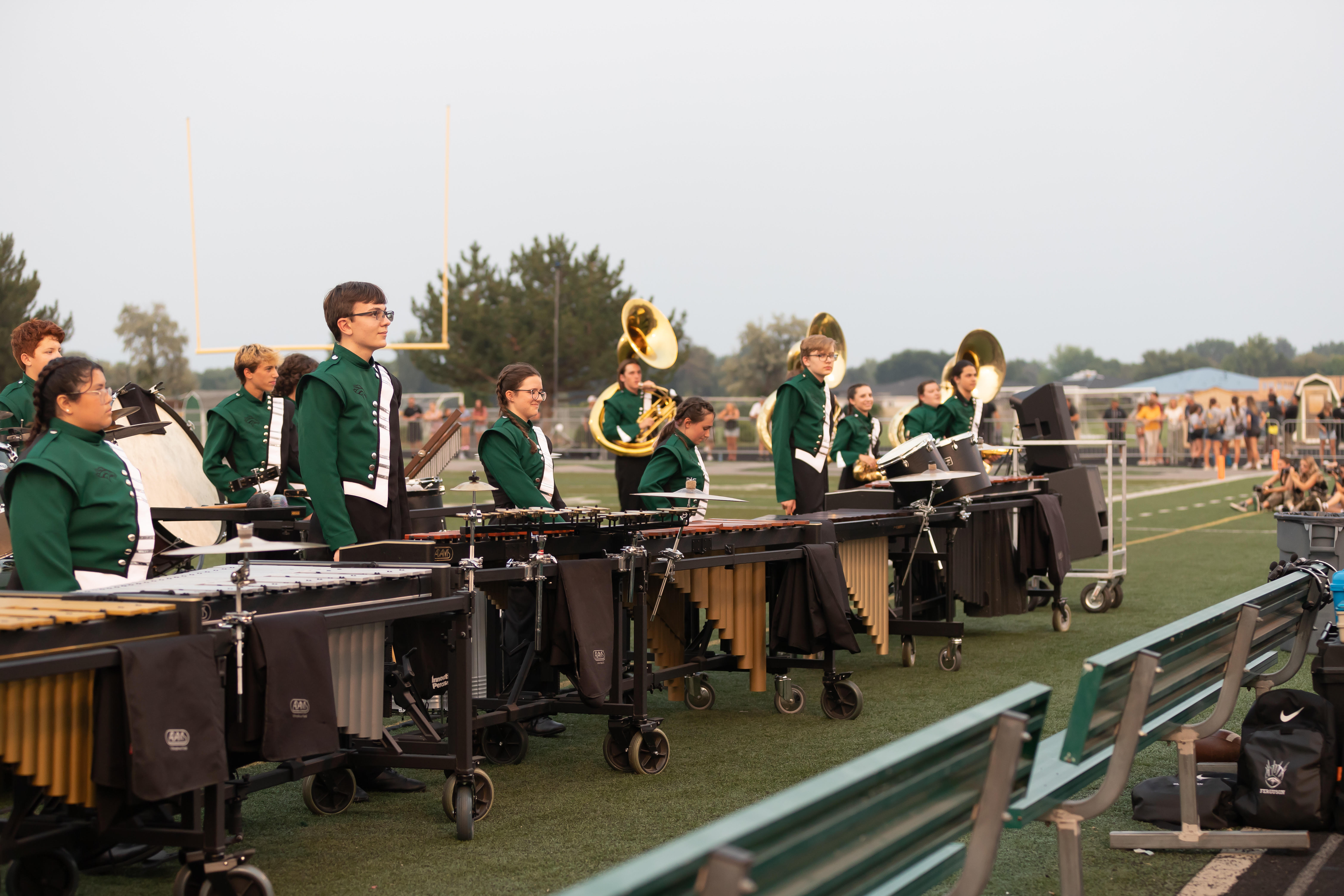High school students in uniforms play marimba and other mallet percussion instruments on a football field.