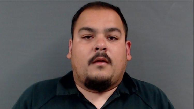 Law enforcement booking photograph of a man in a dark collared shirt.