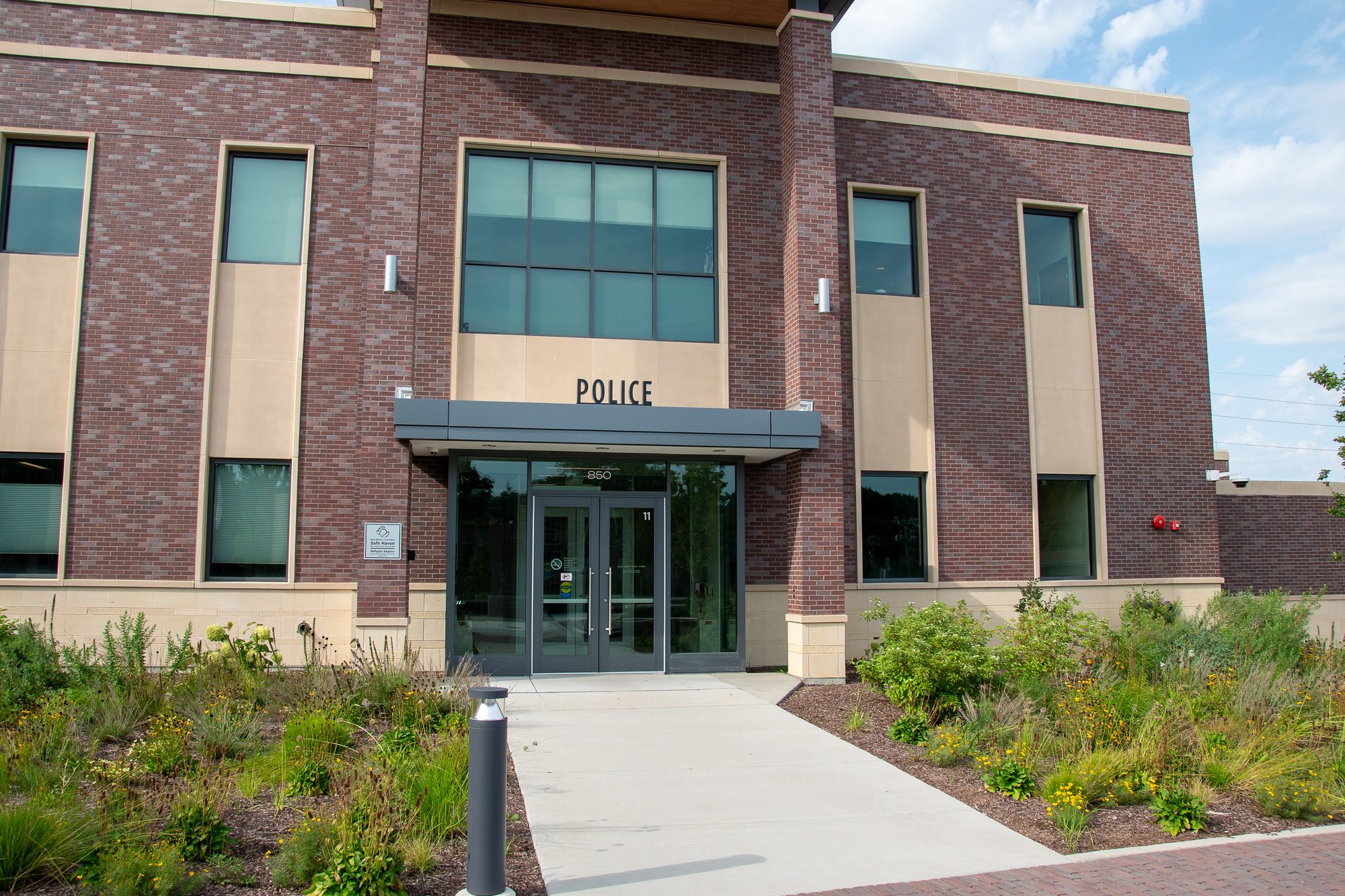 Brick police station exterior with glass entrance doors and landscaping.