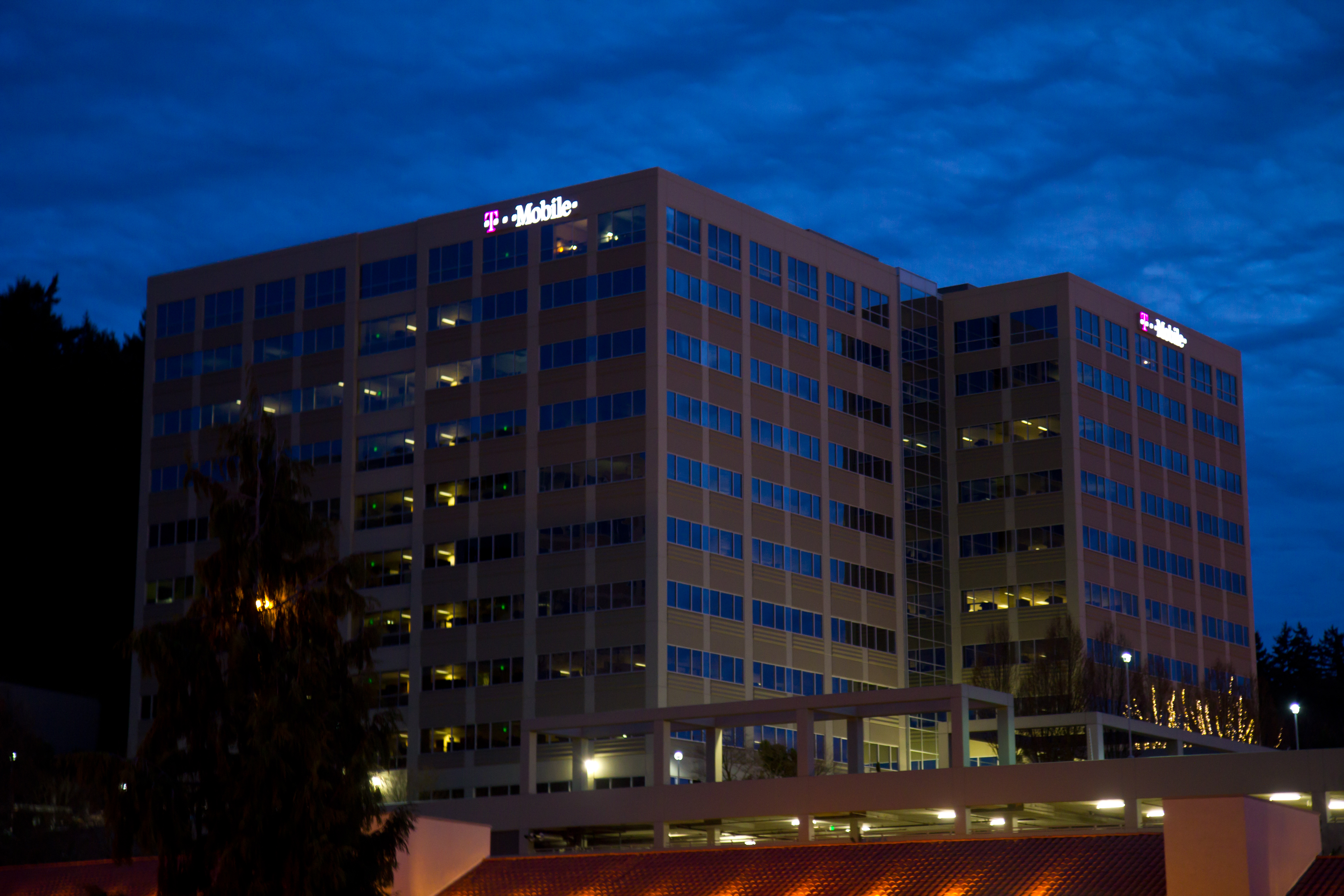 Office building at dusk with illuminated T-Mobile signage on the roofline.