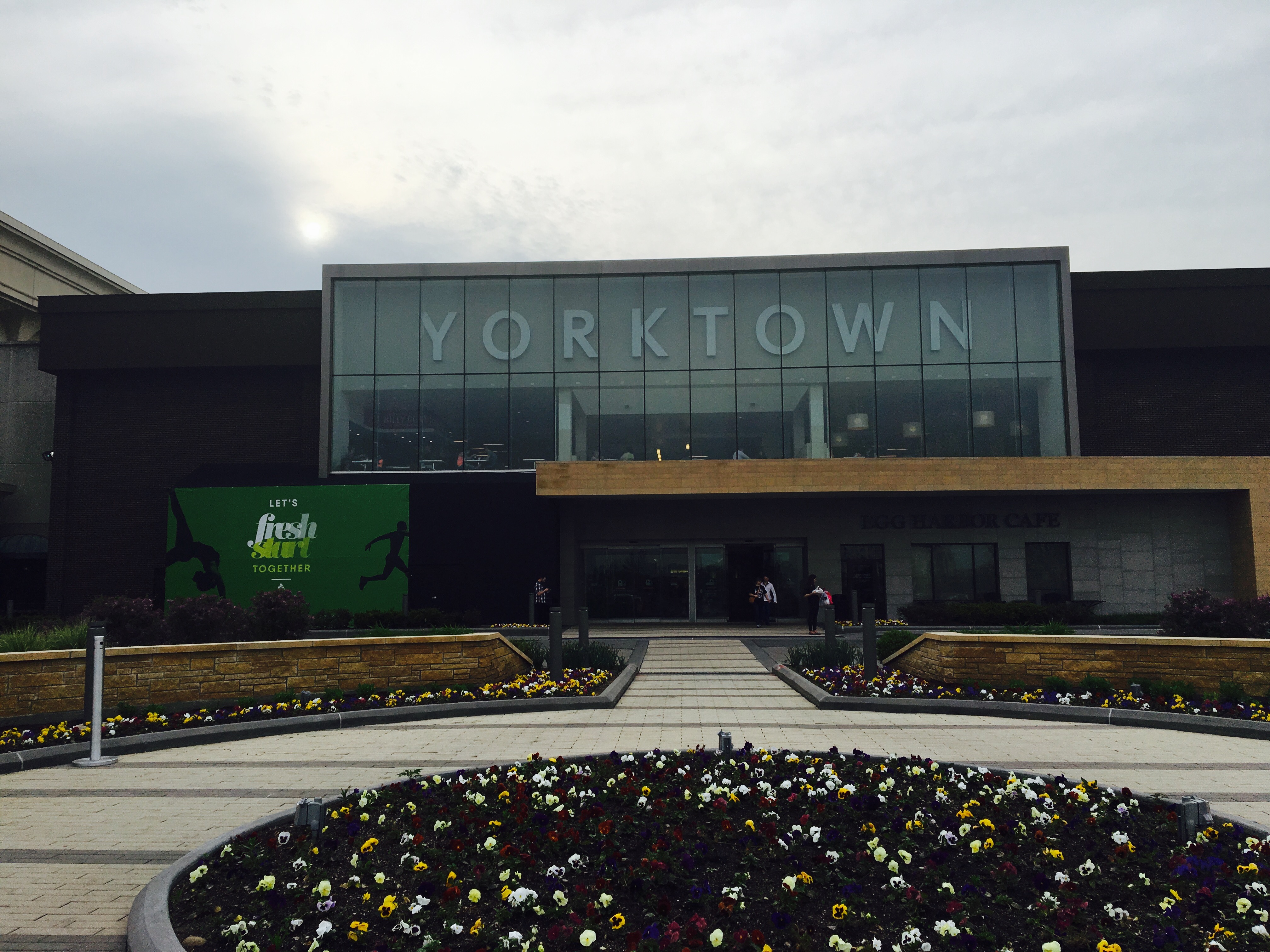 Glass entrance facade of a shopping mall with a large Yorktown sign above the doors.