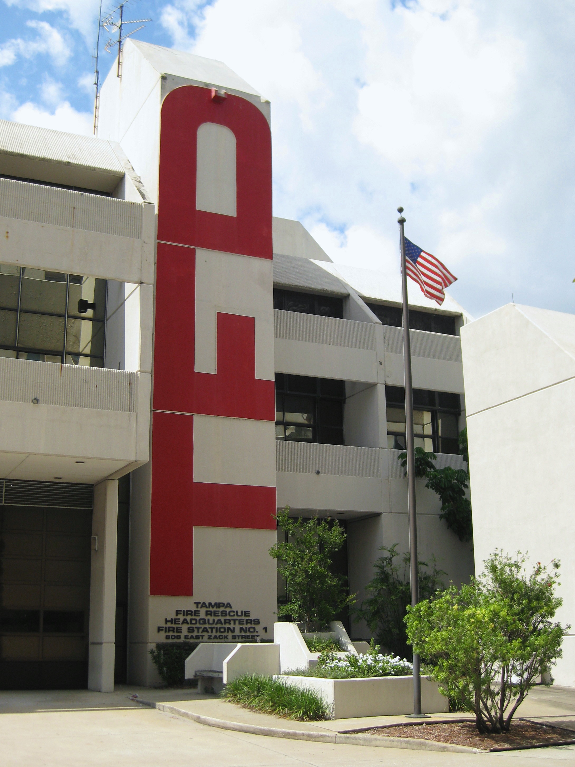 Multi-story fire station building with large red letters on the facade and an American flag.