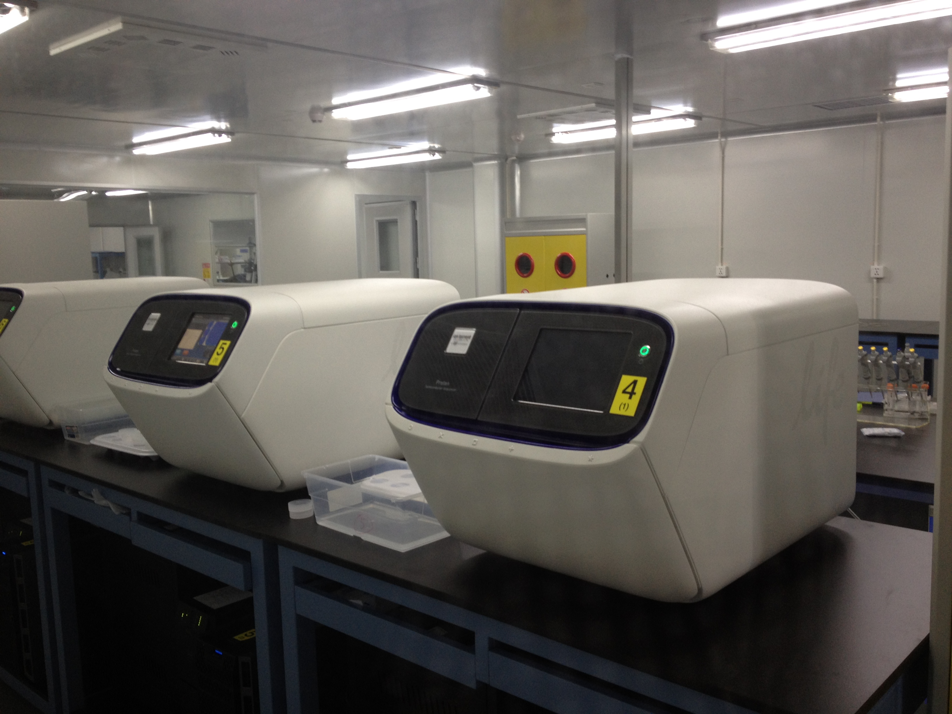 Two white DNA sequencing instruments on a dark laboratory bench.