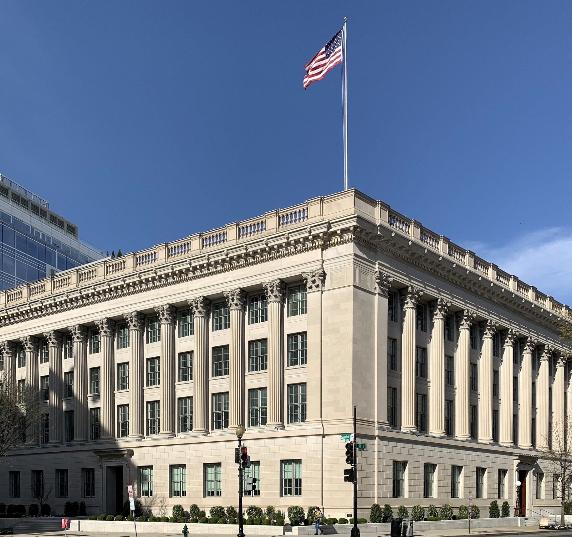 Neoclassical stone building with tall columns and an American flag on the roof.